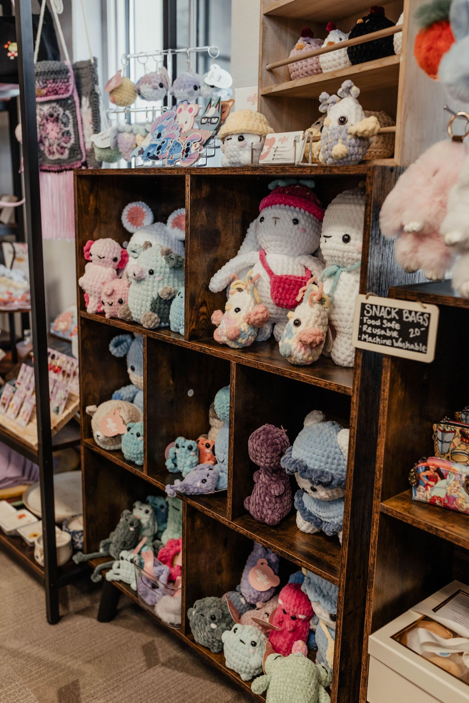 Display of cute plush animals and stuffed toys arranged in wooden retail shelving units.