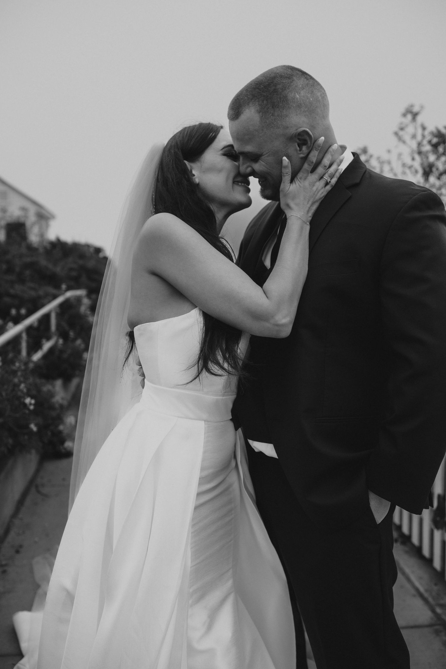 A romantic black and white wedding photo capturing a tender kiss between newlyweds.