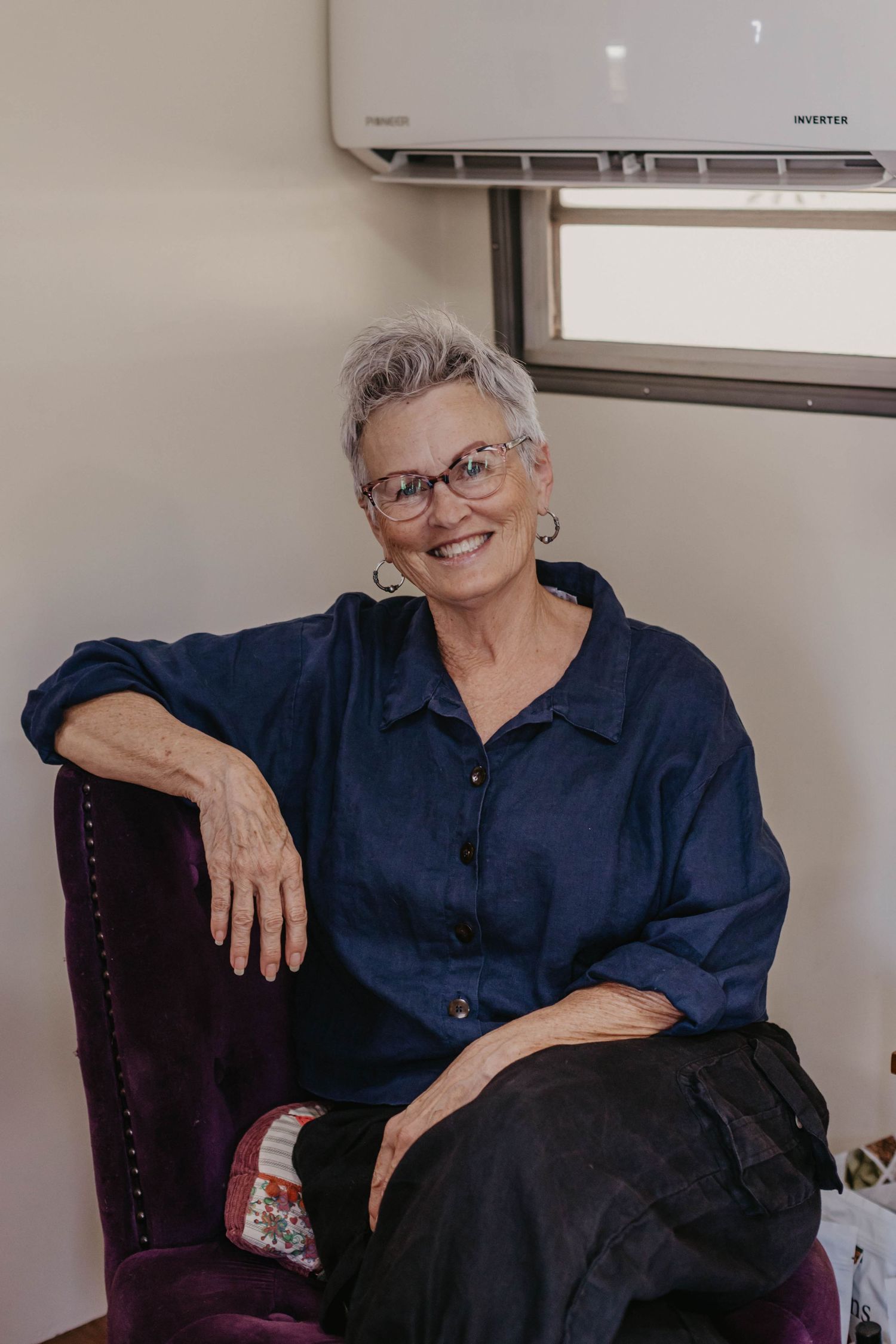 Person in navy blue shirt relaxing on dark upholstered chair.