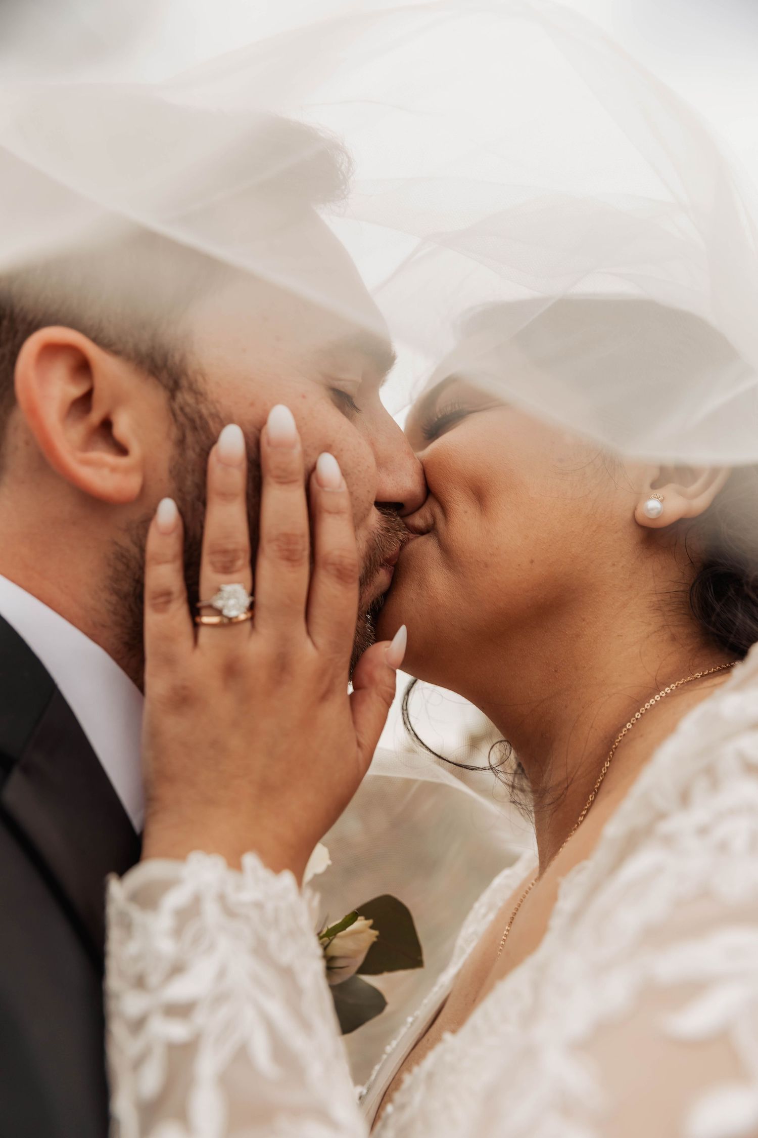 Close-up of a tender wedding kiss with hands gently cradling faces.