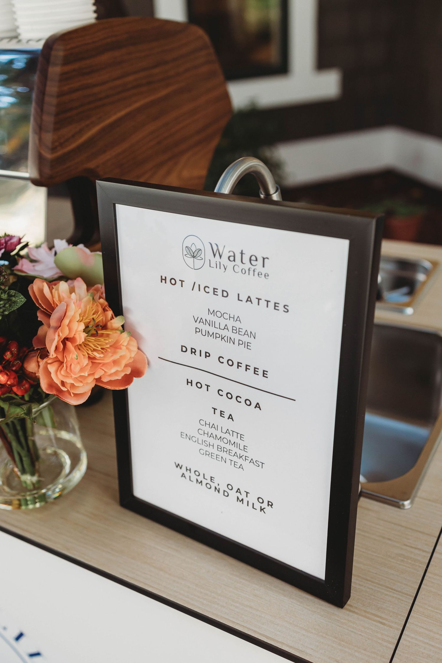 Menu signs displaying drink options like lattes and hot cocoa with orange flowers in a vase.