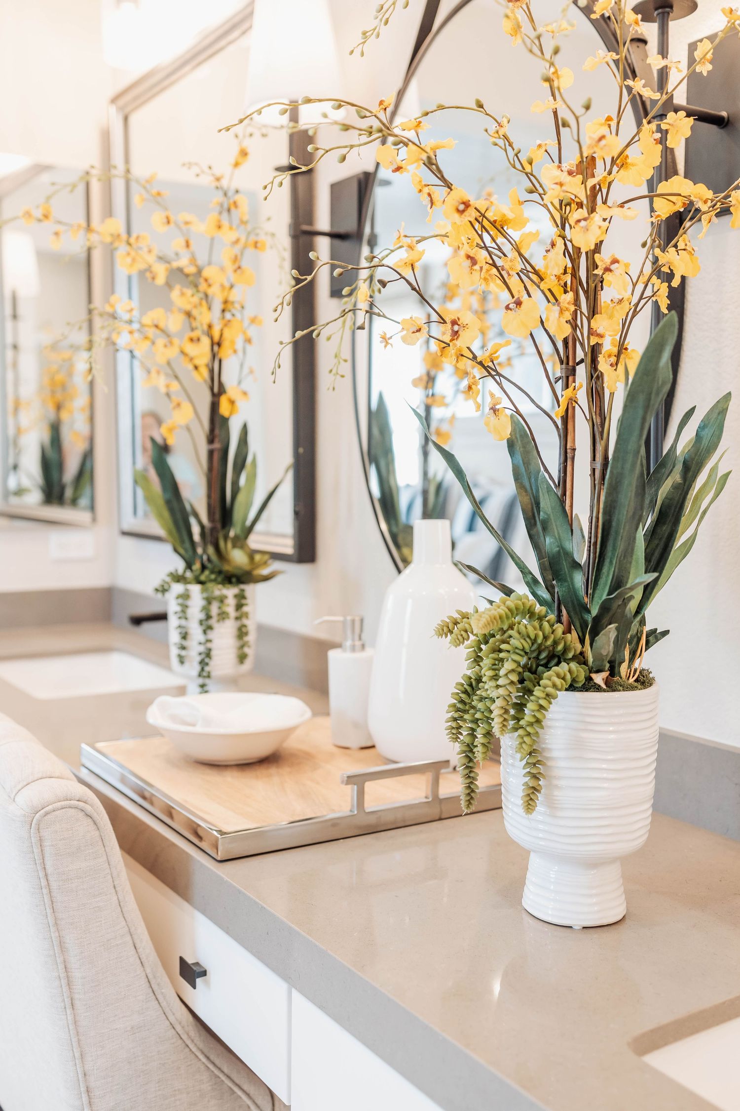 White bathroom vanity decorated with yellow orchids and ceramic accessories creating an elegant display.