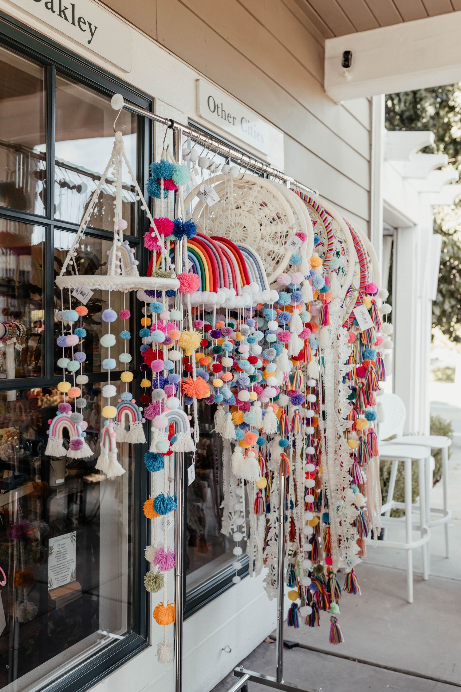 Colorful hanging tassel and pompom decorations displayed outside a boutique storefront.