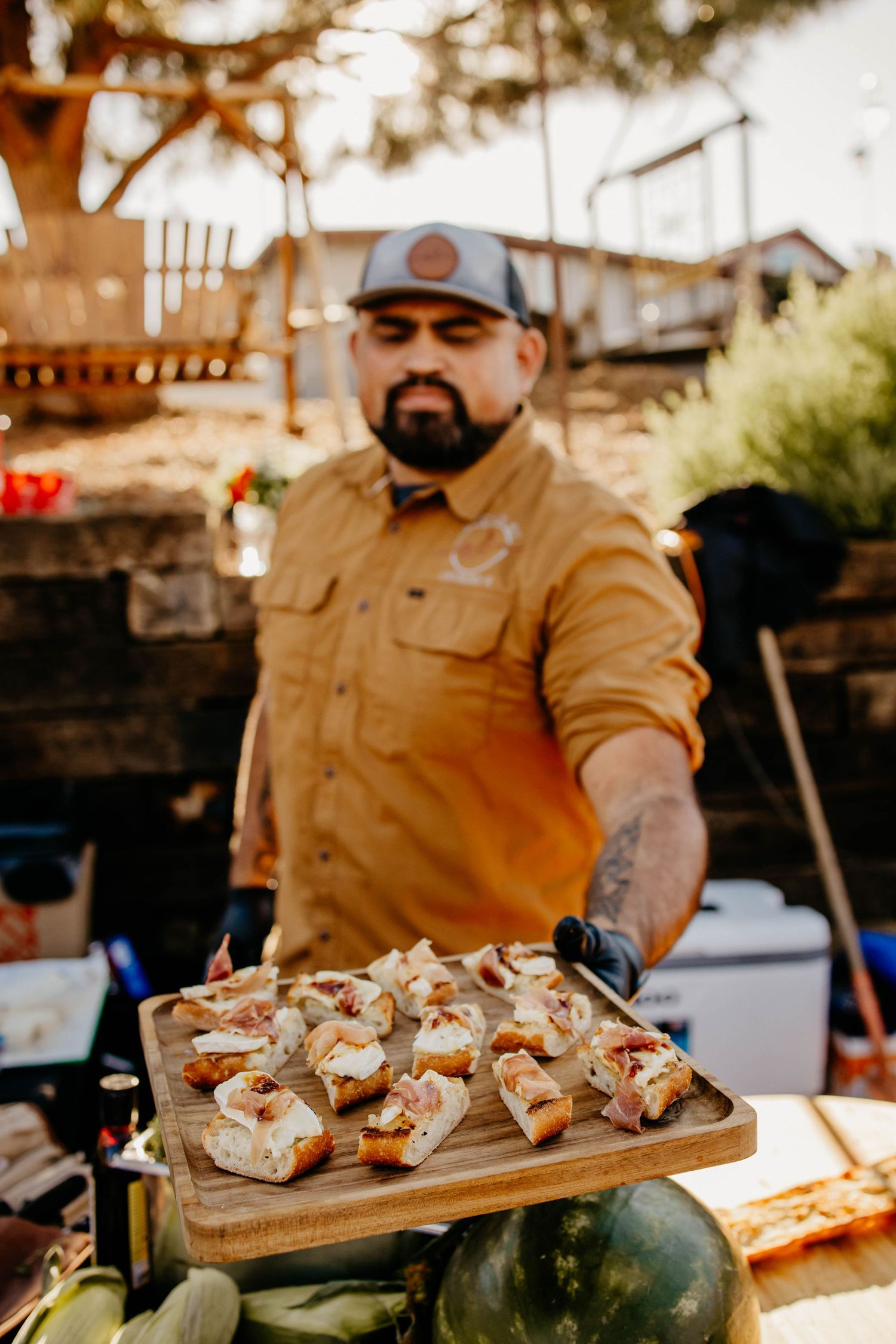 Appetizers beautifully plated on wooden serving boards at an outdoor catering event.