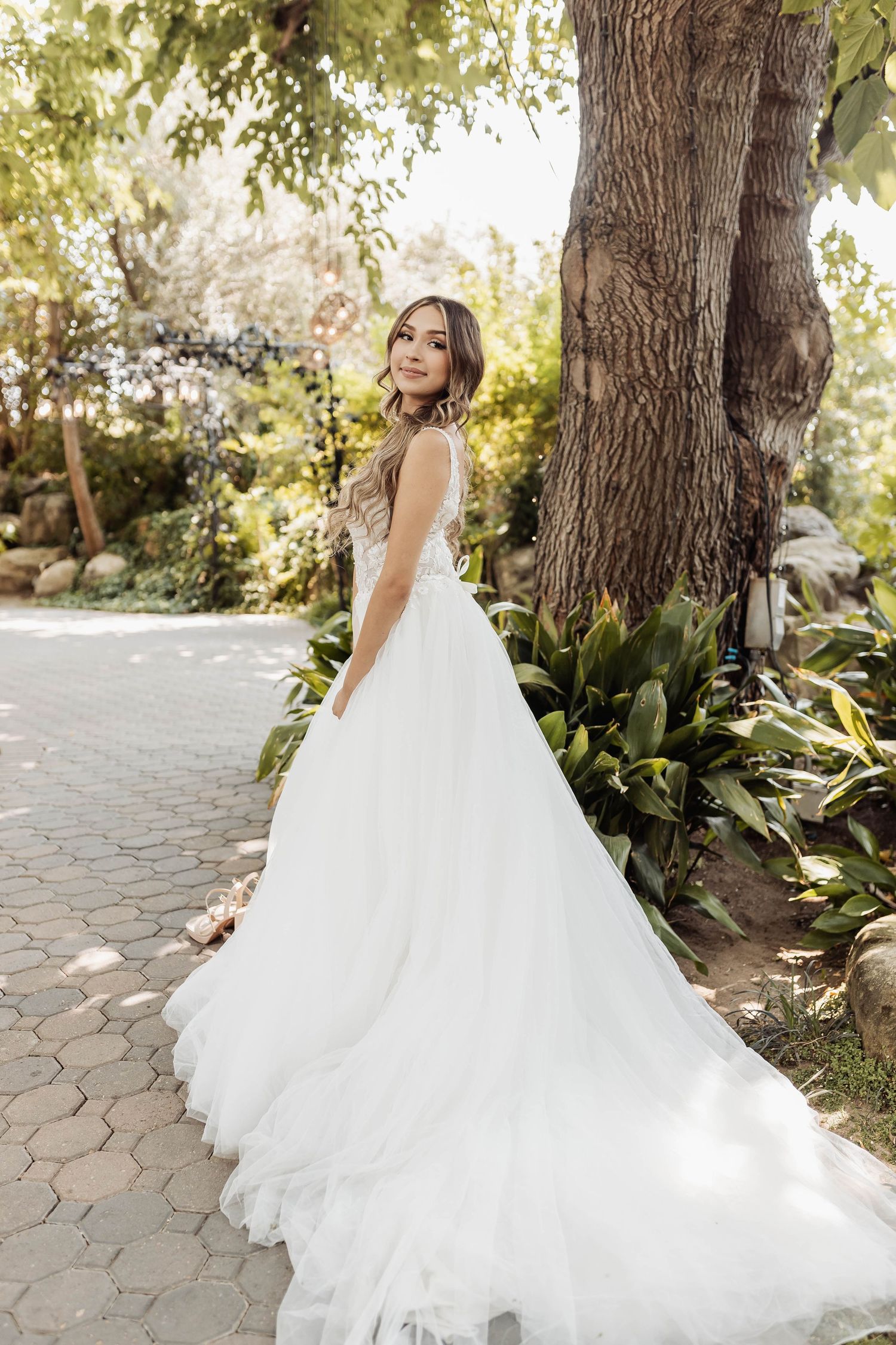 Romantic bridal photos showing flowing tulle wedding dress twirling in a garden pathway.