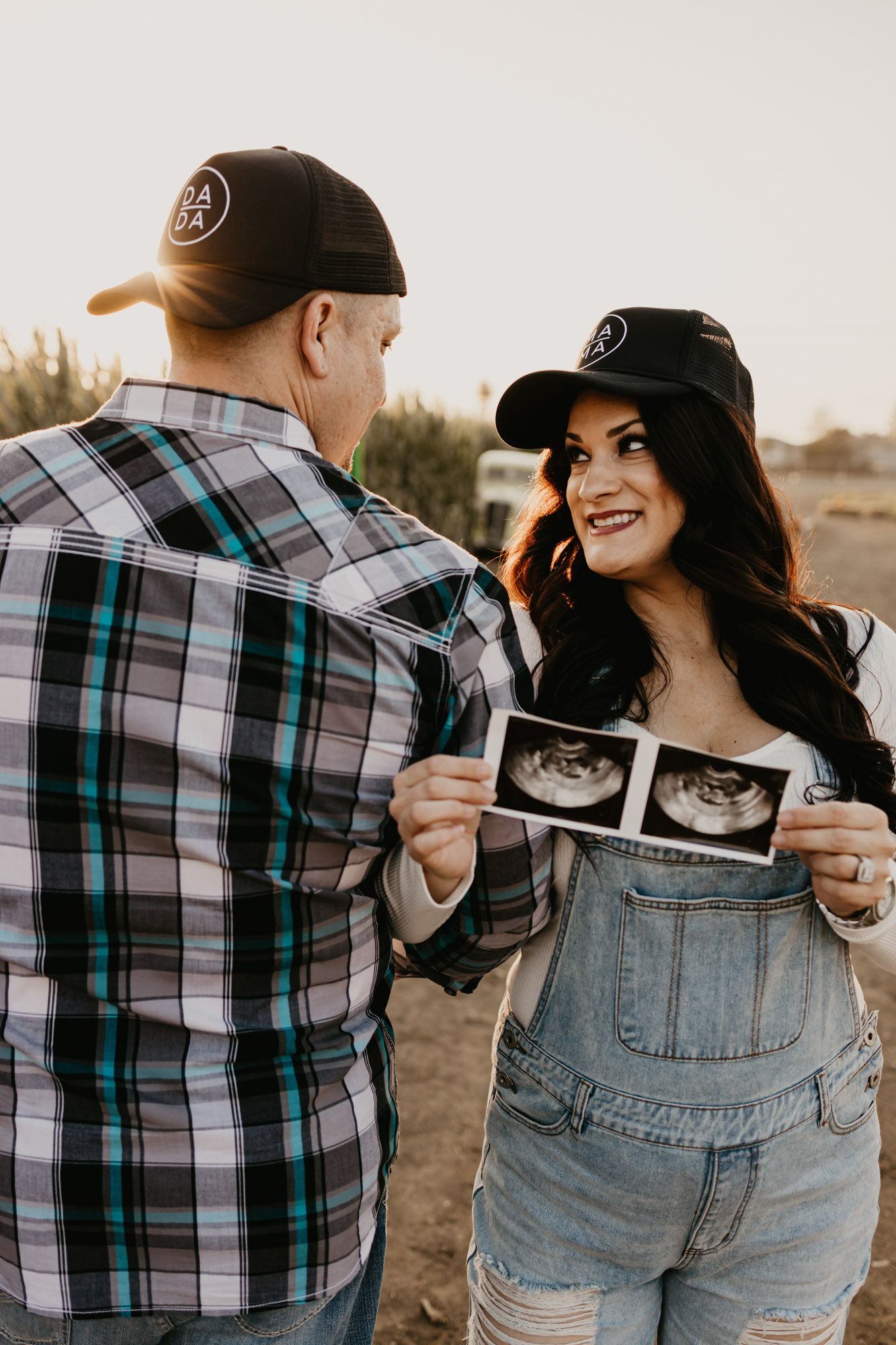 Happy couple showing ultrasound photos during pregnancy announcement photoshoot.