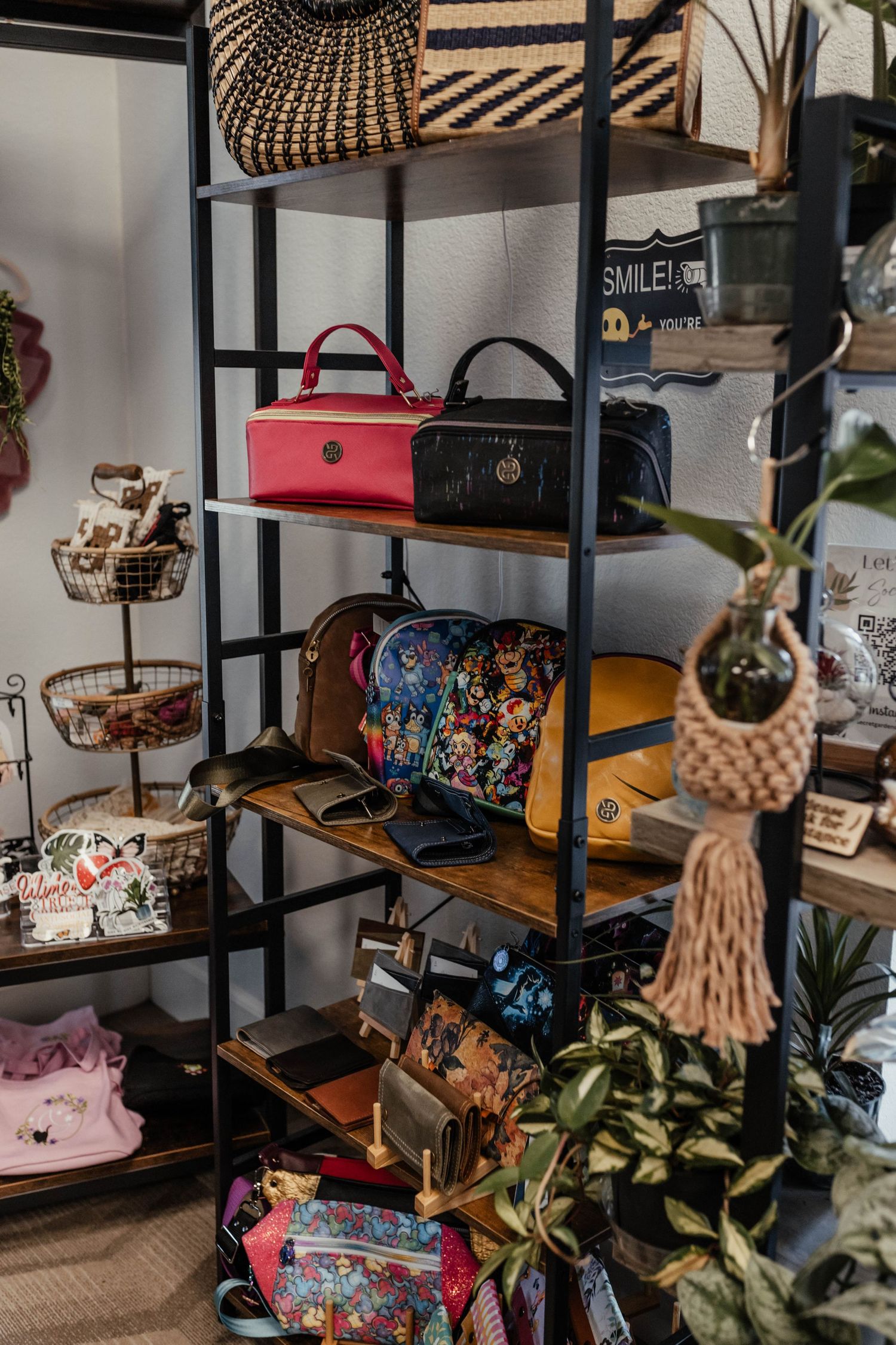 Black metal retail shelving unit displaying colorful handbags, accessories and decorative items.