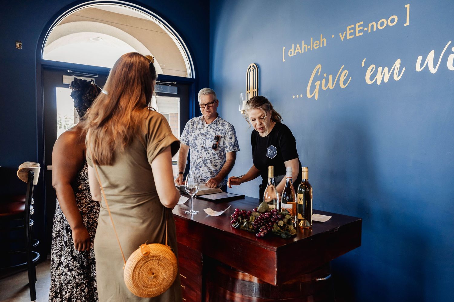 Group gathering in front of blue wall with decorative text signage in restaurant setting.