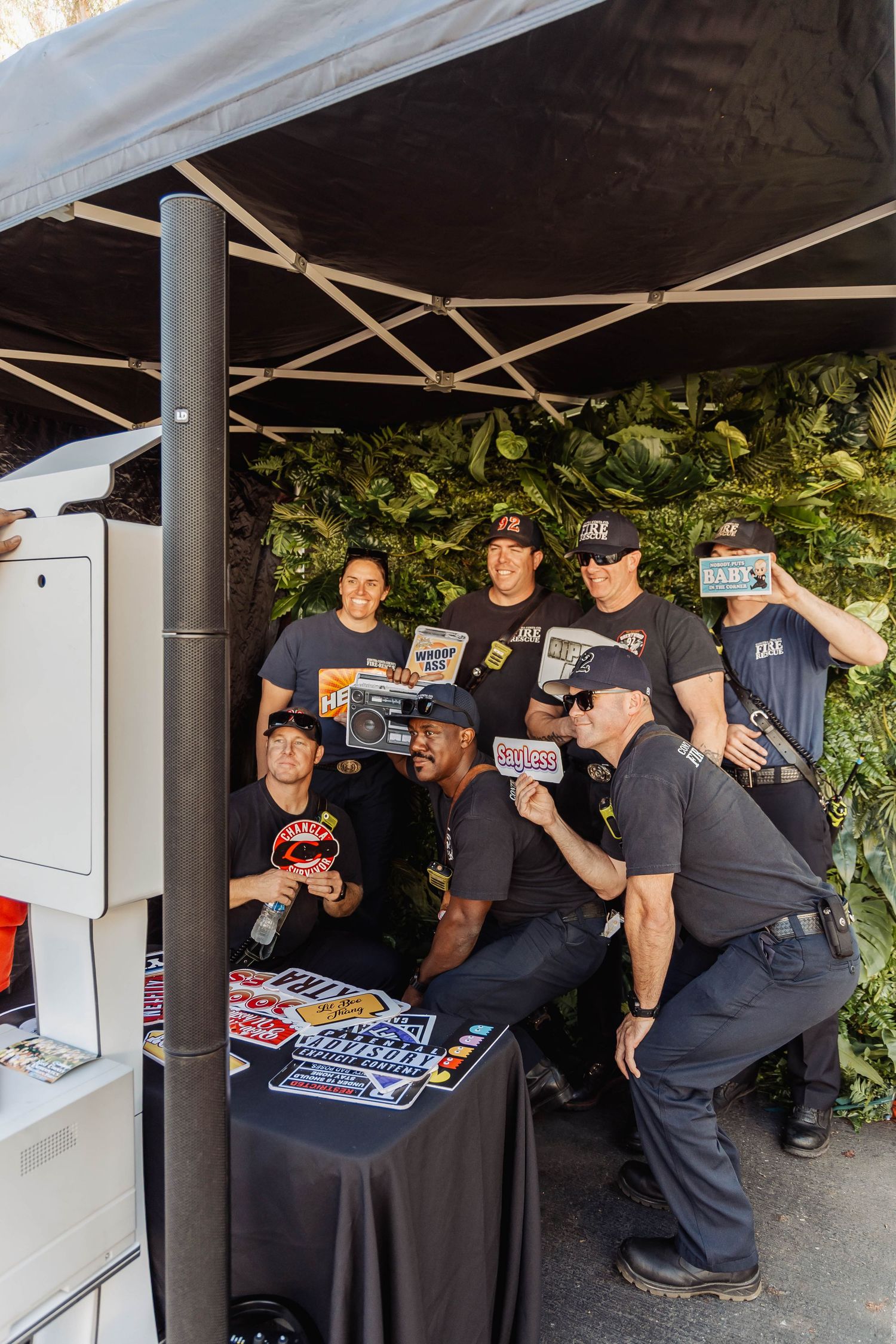 People in dark clothing gathered under a tent looking at merchandise or materials.