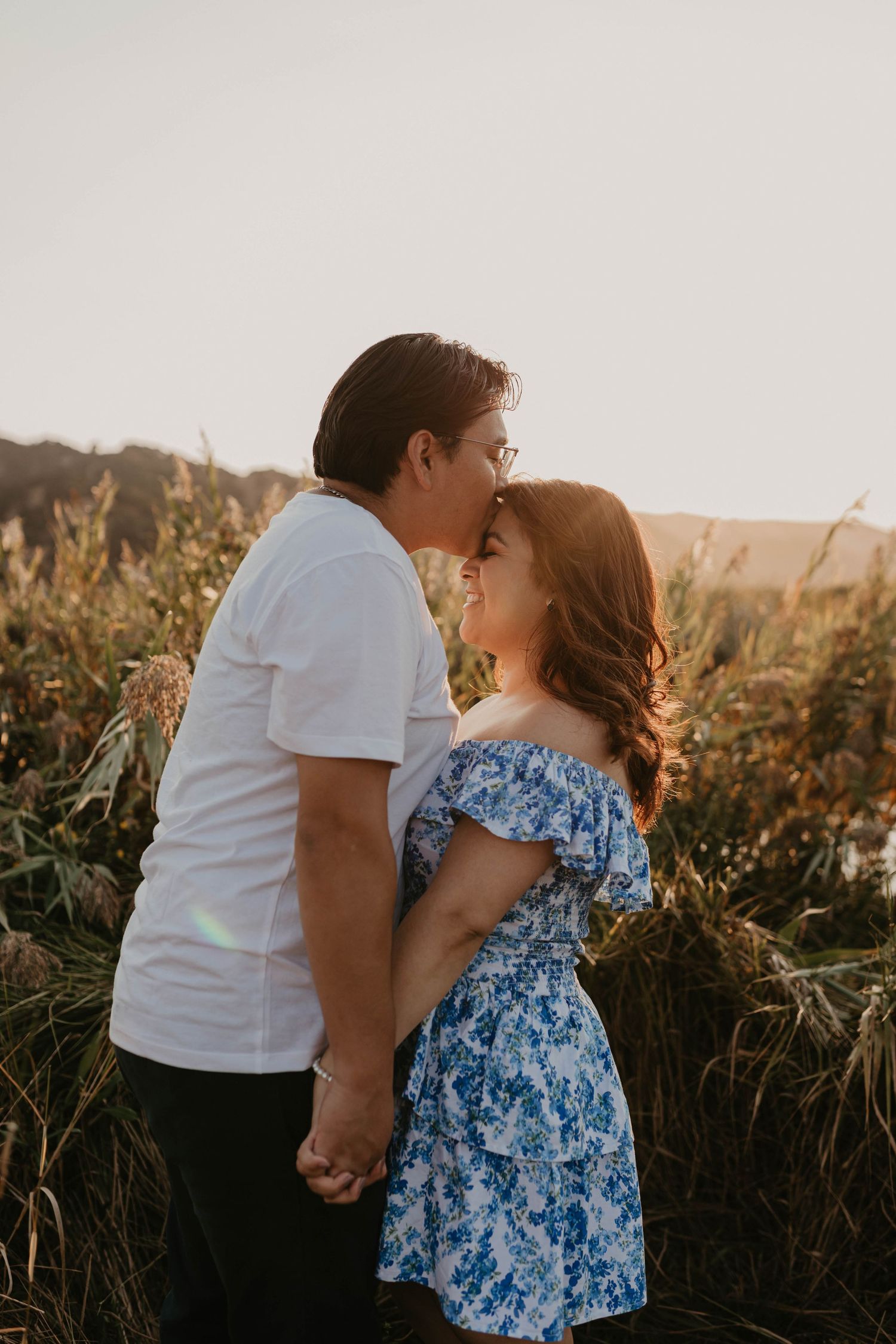 Couple sharing romantic moment in field during golden hour.