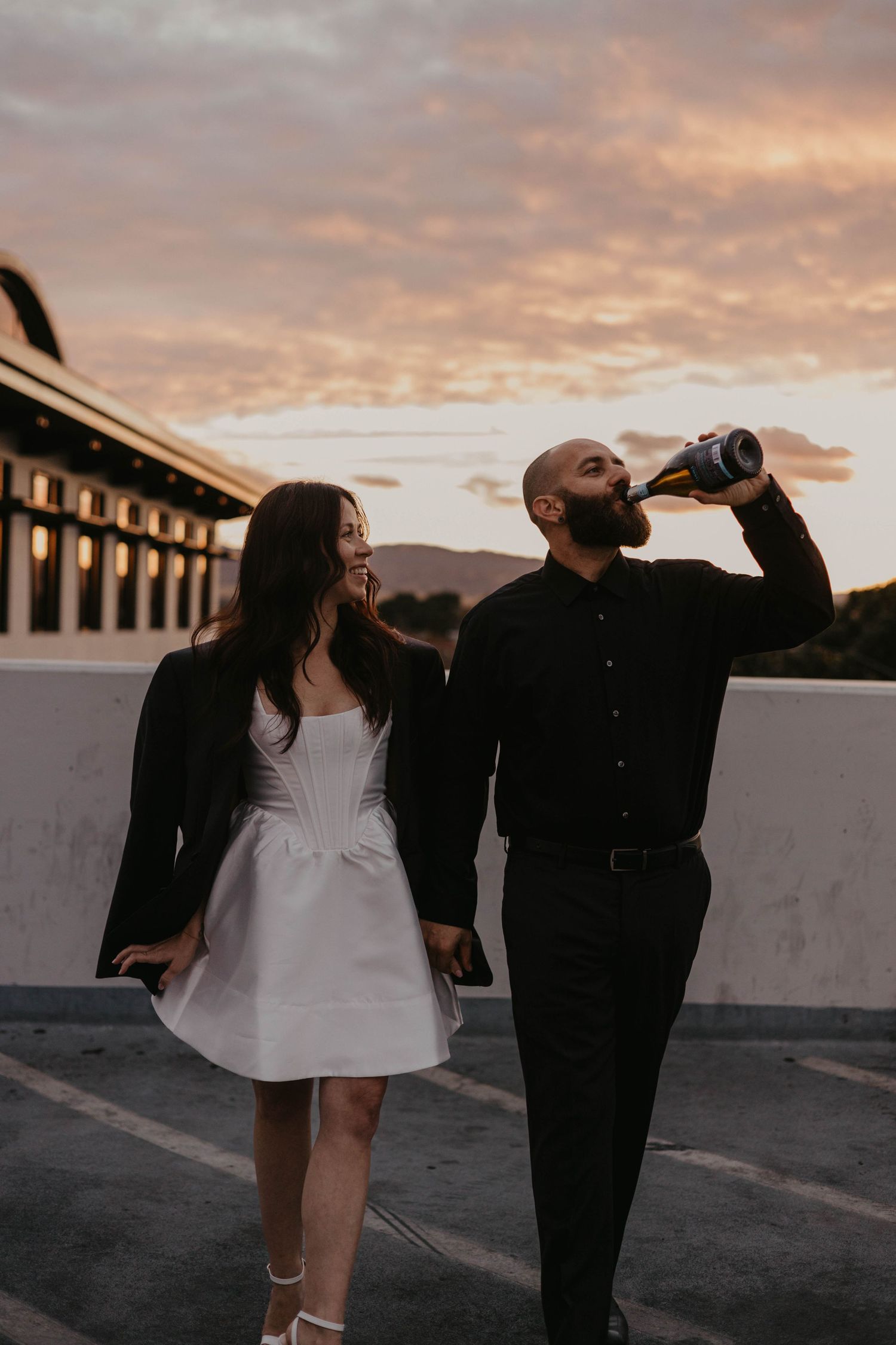 Couple sharing a casual moment at sunset on a rooftop with mountains in background.