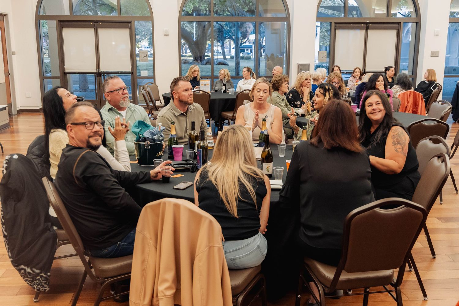 Guests networking at round tables during a formal banquet event in an elegant venue with large windows.
