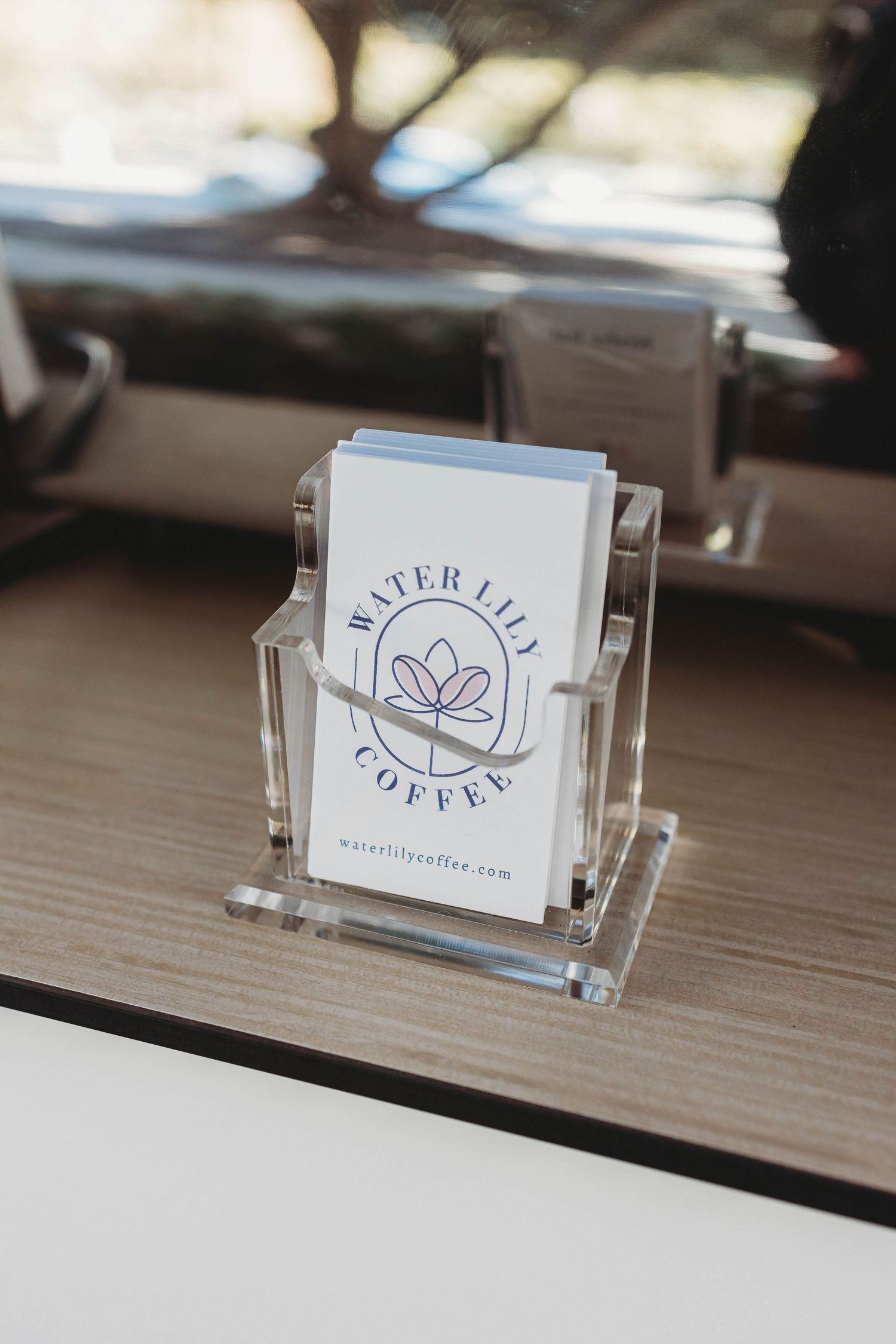 Business card holder displaying minimalist coffee shop logo on wooden counter.