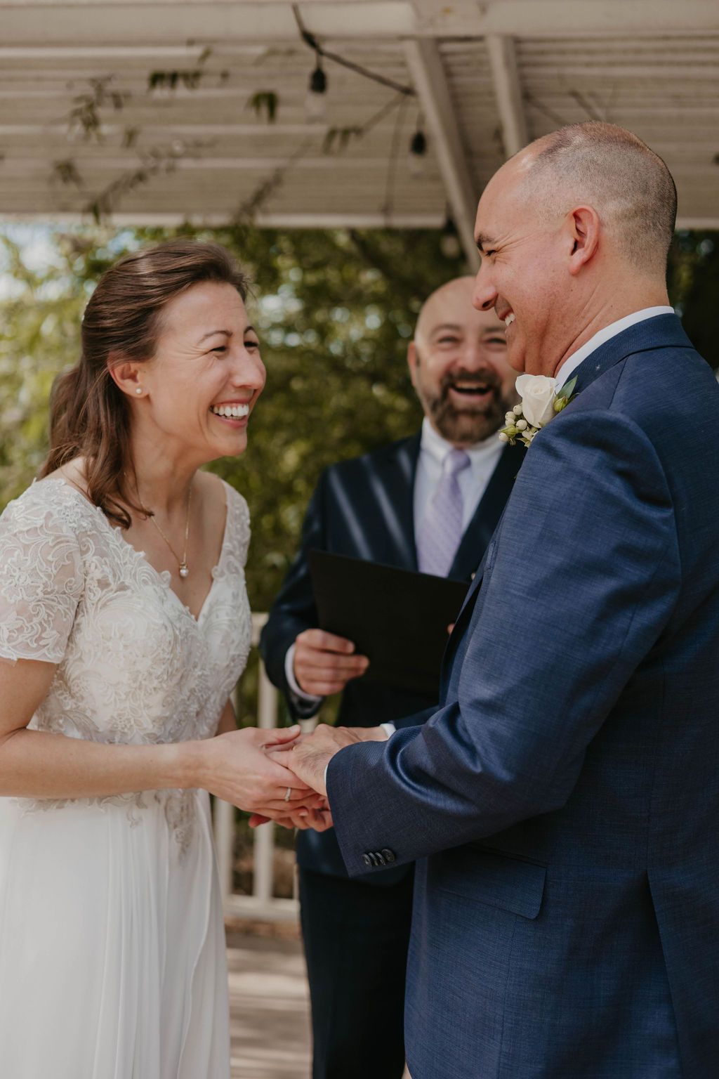Happy couple shares a moment during their wedding ceremony on a covered porch.