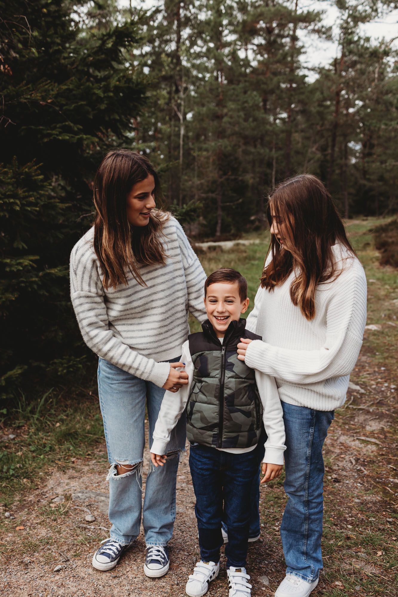 Three people in casual winter wear standing on a forest trail together.