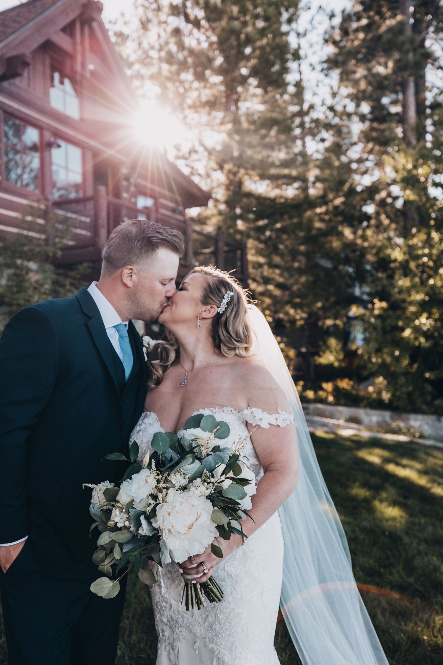 Sunlit wedding portraits captured in front of rustic building during golden hour.