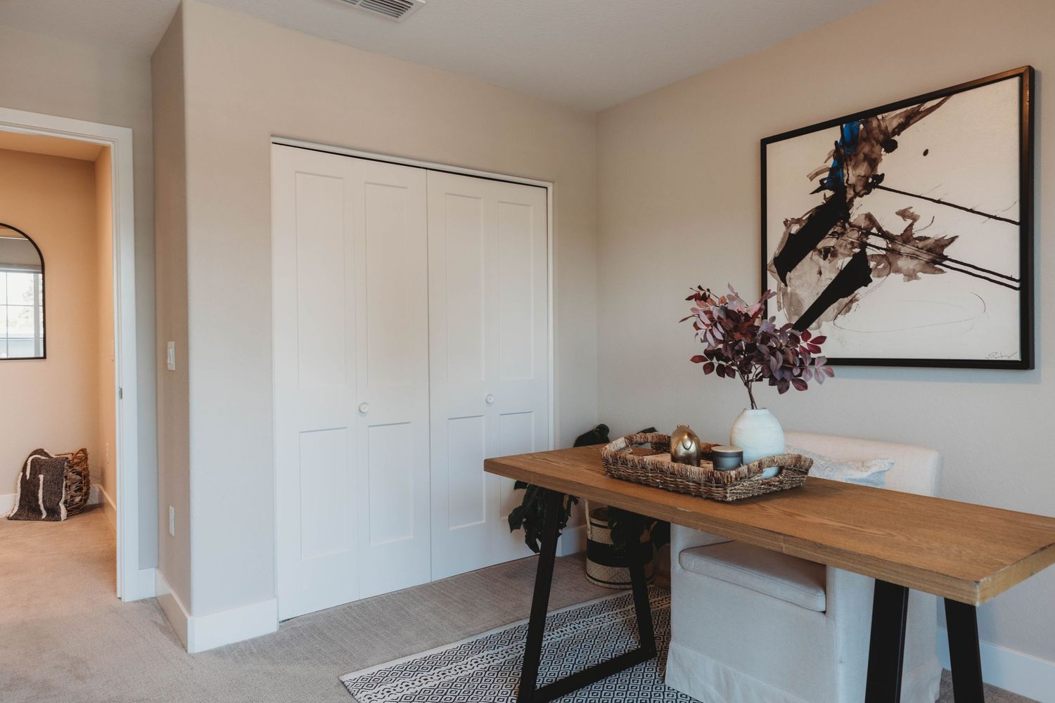 Contemporary entryway featuring wood console table, abstract wall art, and white closet doors.