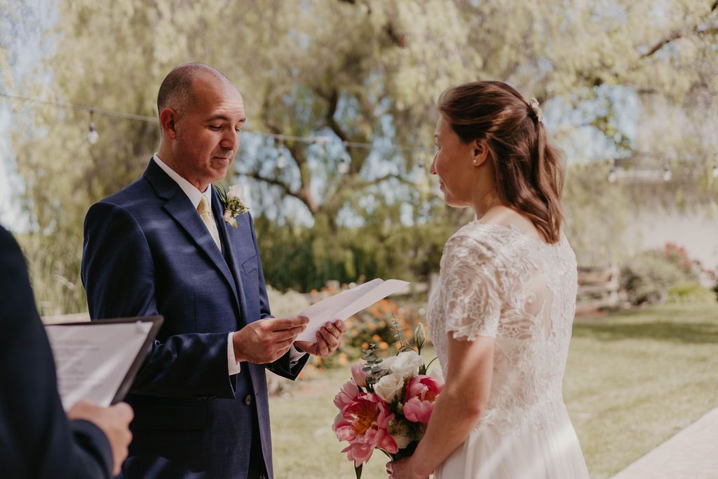 A romantic outdoor wedding ceremony with exchanging of vows and pink floral bouquet.