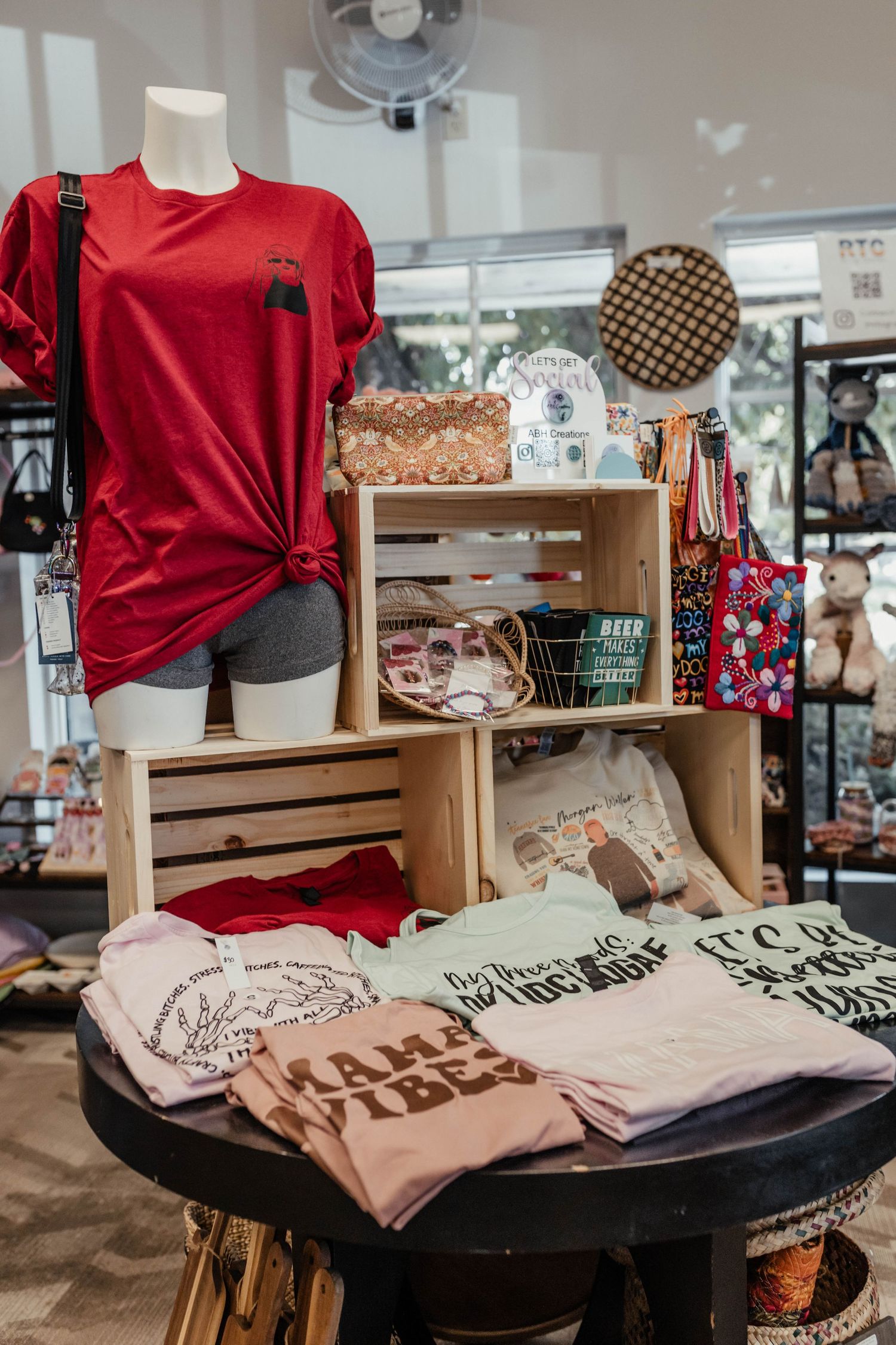 Red and pink t-shirts displayed on wooden crates in boutique retail setting.