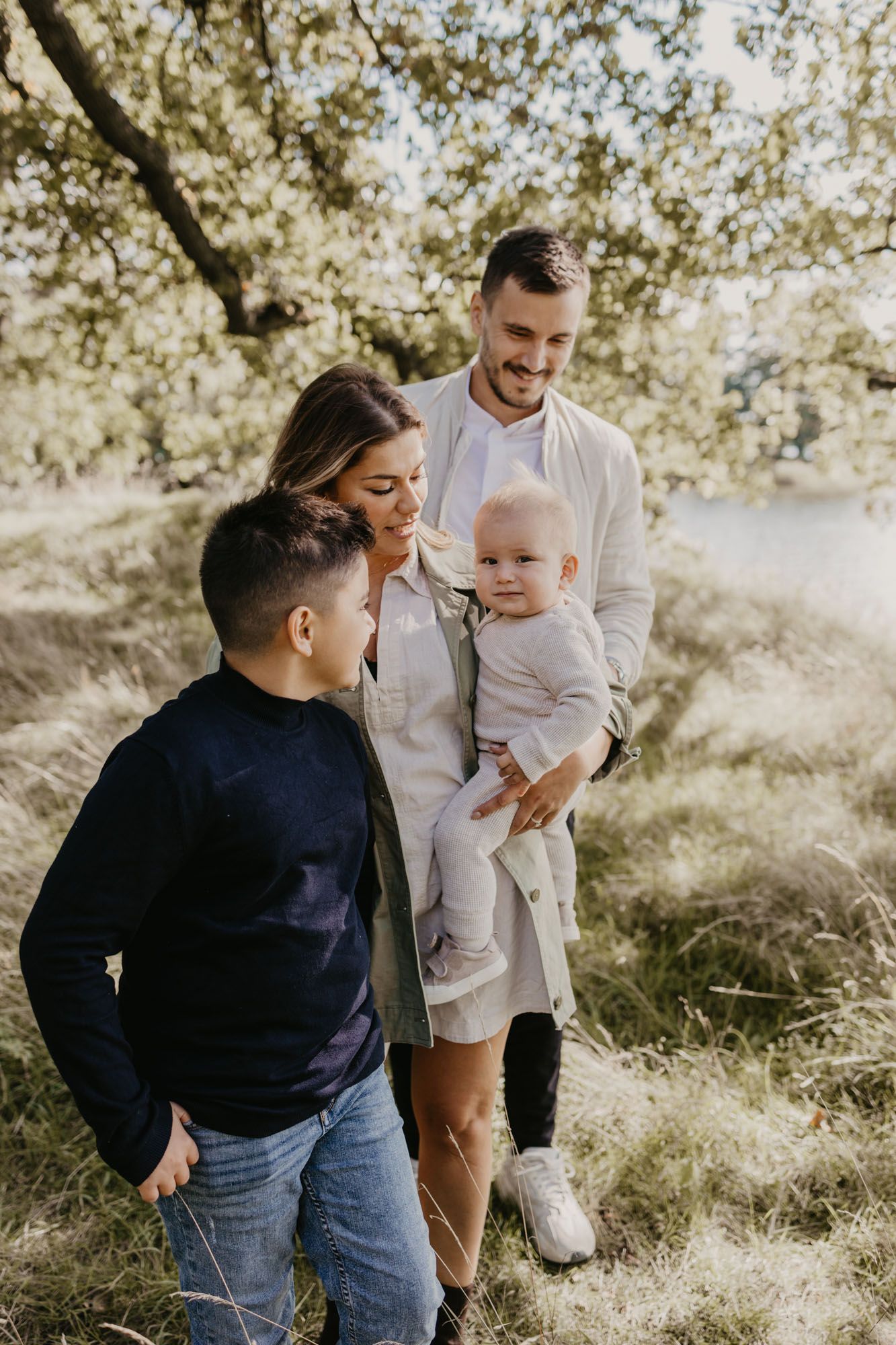 Candid family moment captured in a sun-dappled outdoor setting with natural lighting.