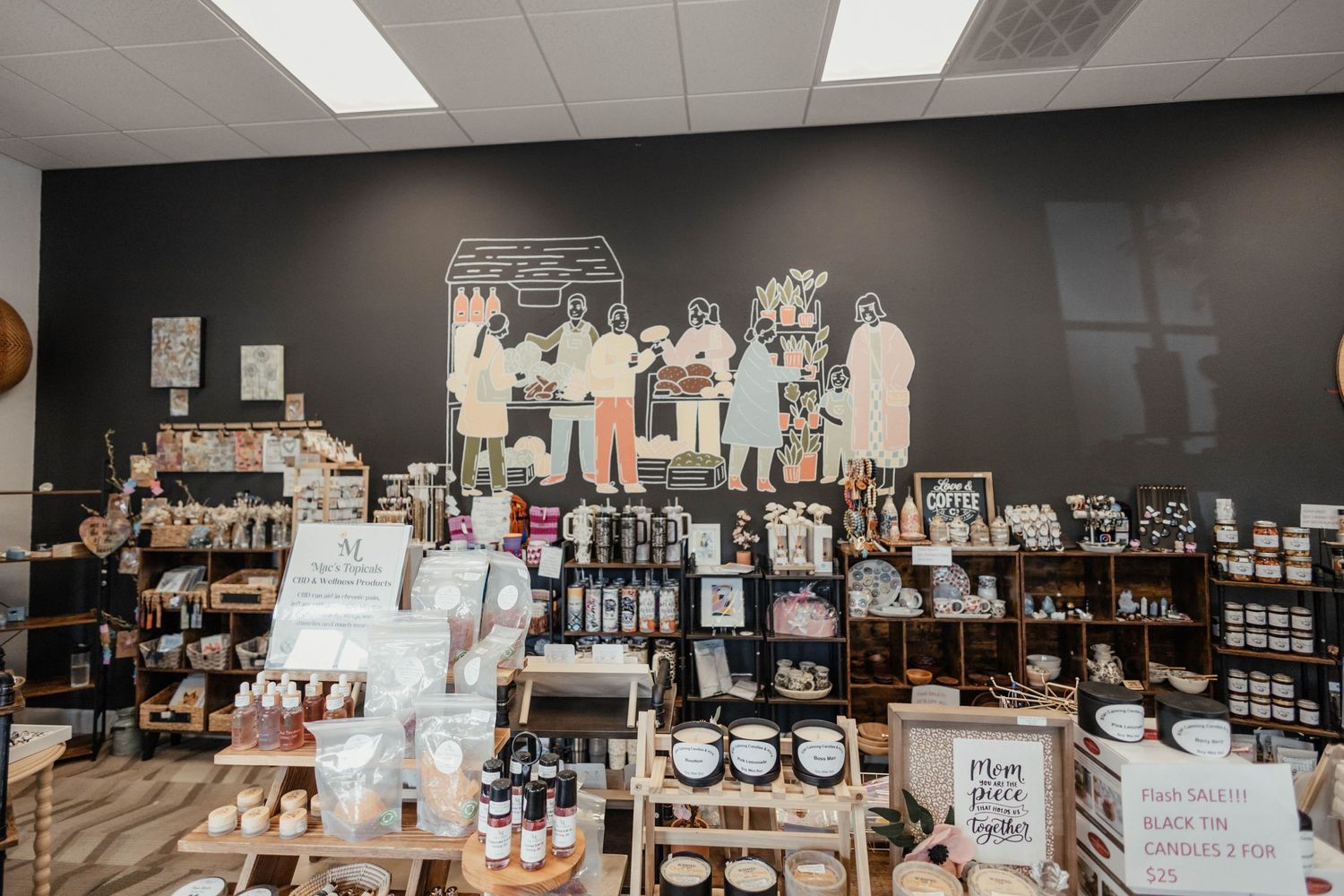 Interior view of a coffee shop with artistic wall mural and retail shelving displaying coffee products and merchandise.
