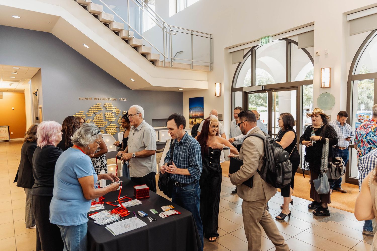 Event attendees gathering around registration or check-in table in bright indoor venue.