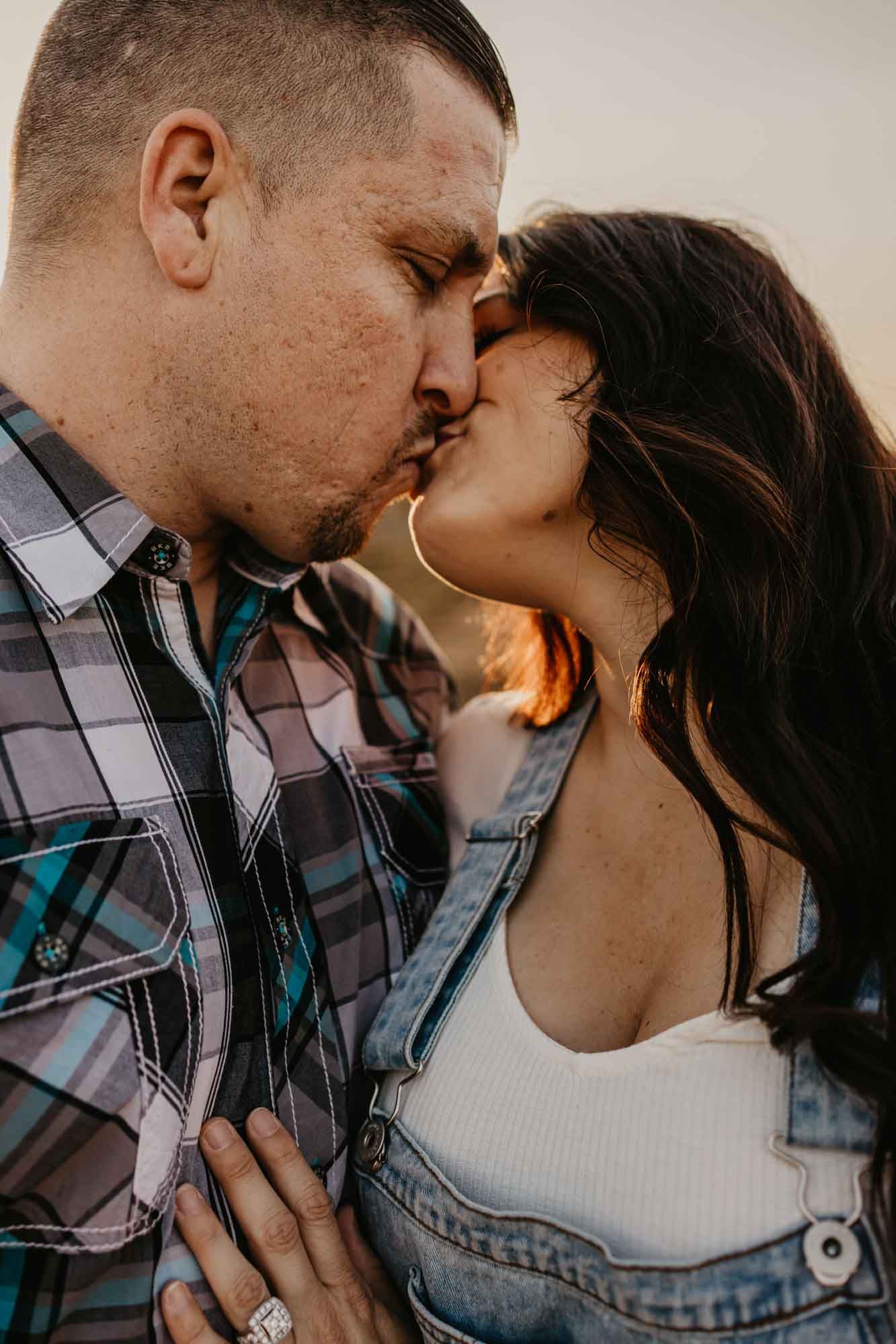 An engaged couple shares a tender kiss during their sunset photoshoot.