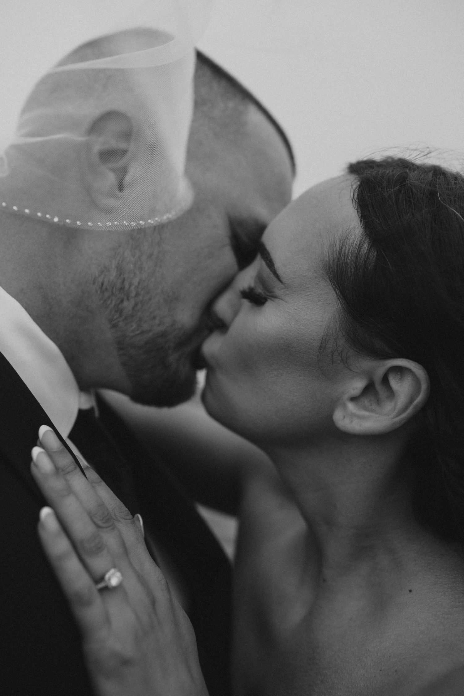 An artistic black and white shot of newlyweds sharing their first kiss.