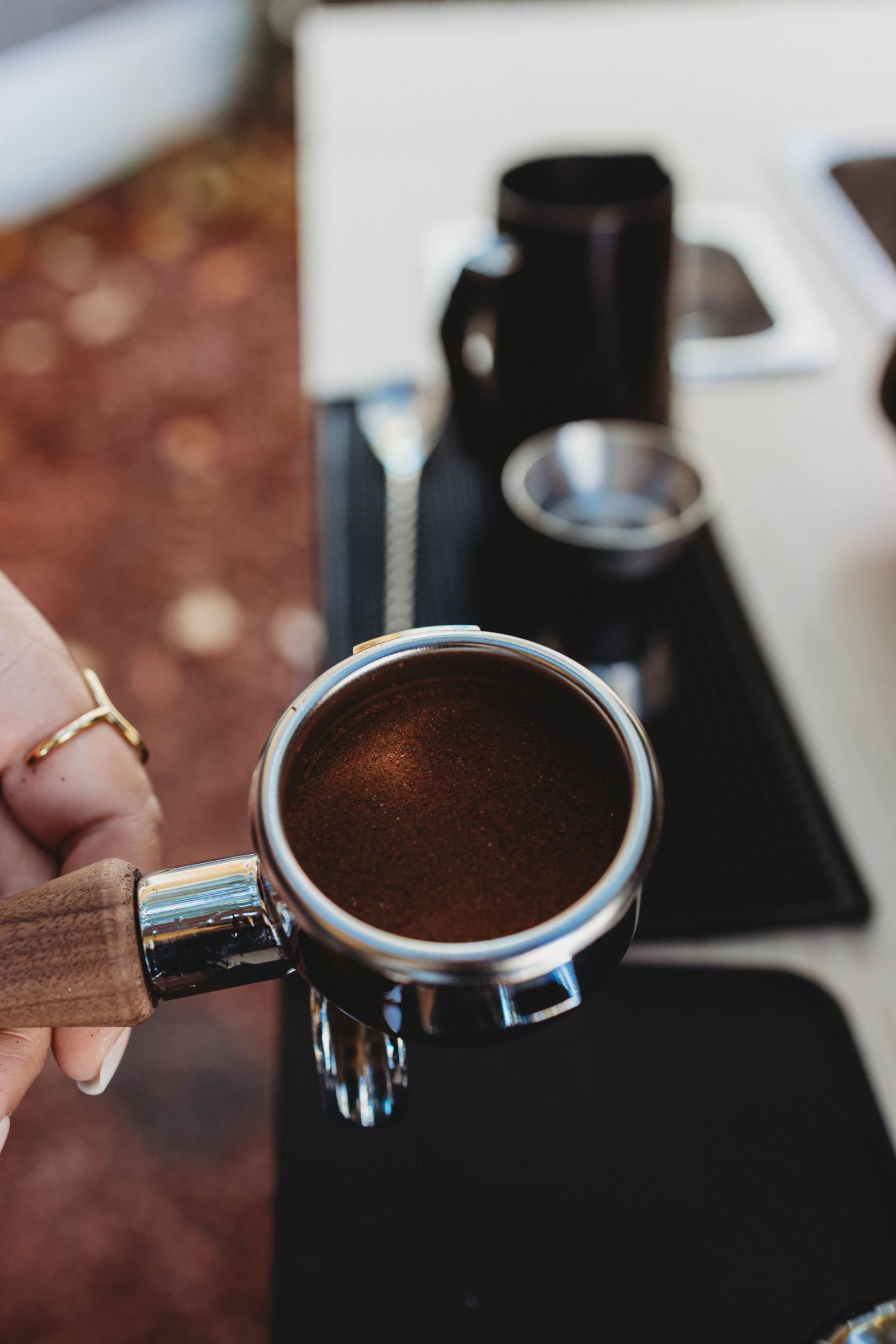 Close-up of espresso tamping process showing coffee grounds in portafilter.