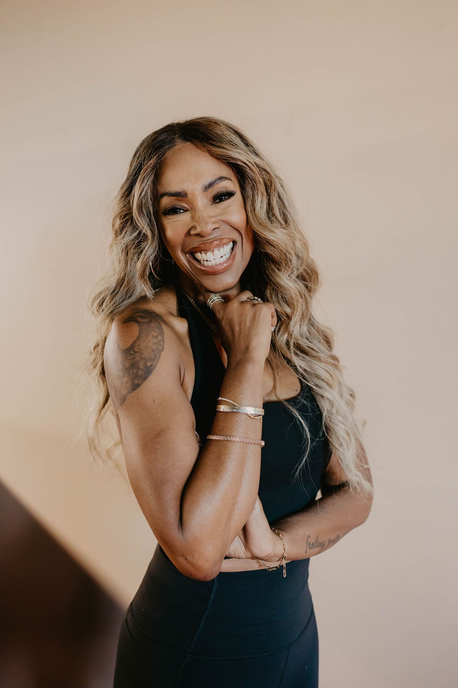 Athletic woman in black tank top smiling and posing against neutral background.