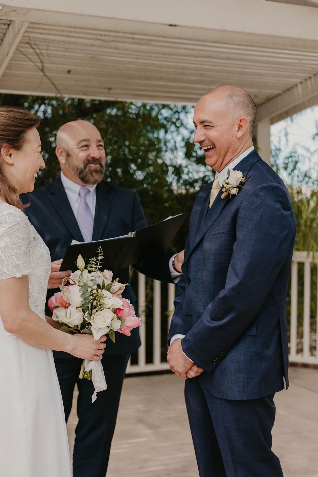 A candid moment of laughter shared during a wedding ceremony under a covered porch.