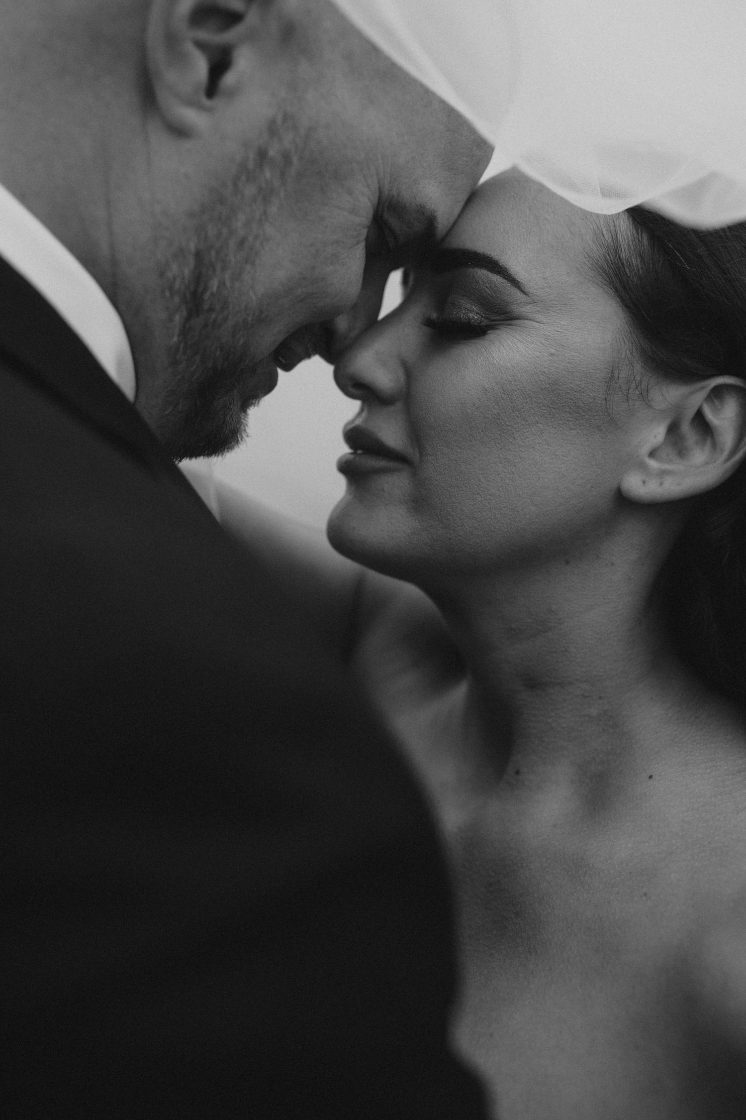 A dramatic close-up black and white wedding portrait capturing an intimate moment.