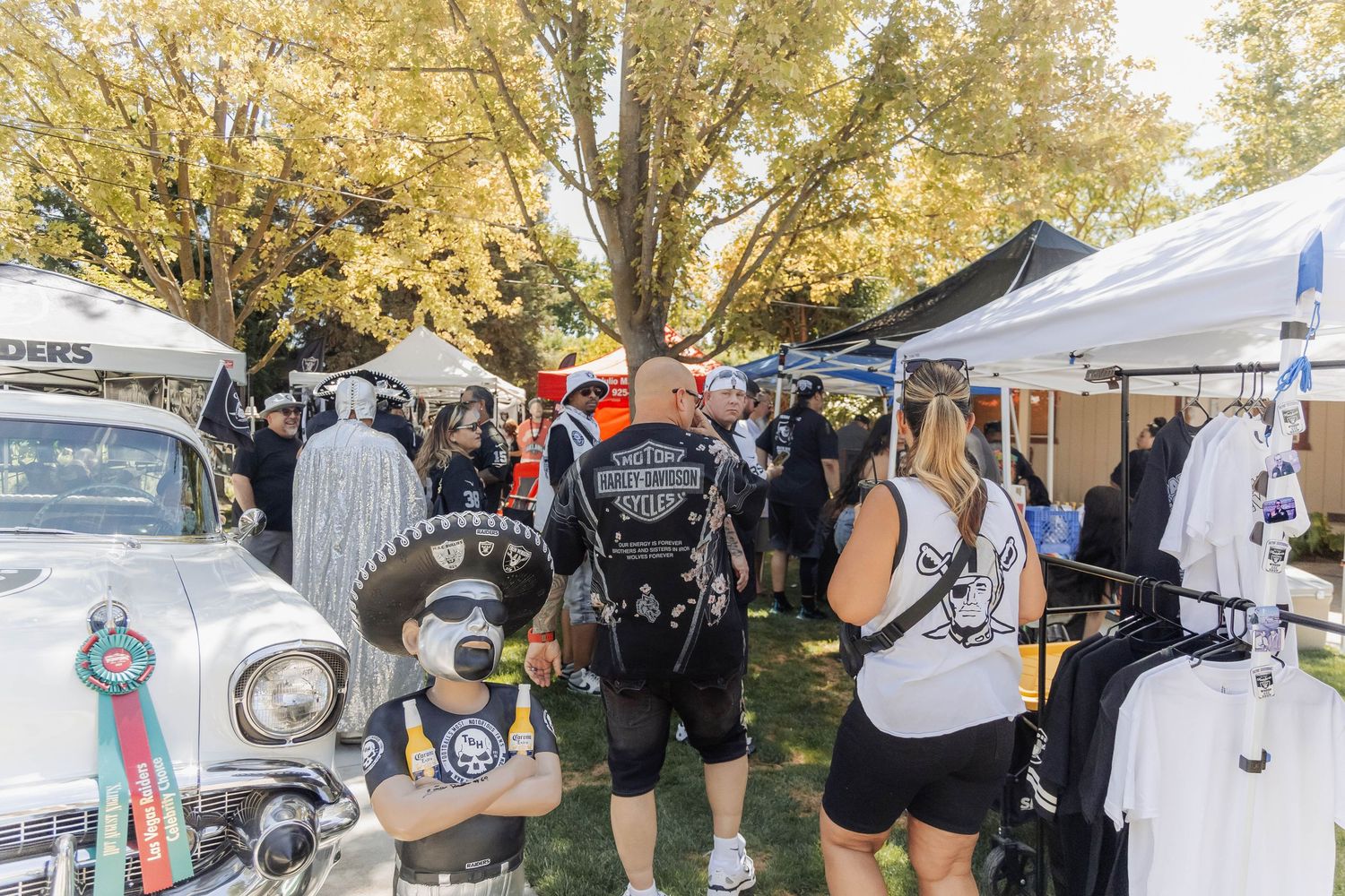 Crowd of people in costumes and Harley-Davidson gear browsing vendor booths at an outdoor motorcycle rally event.