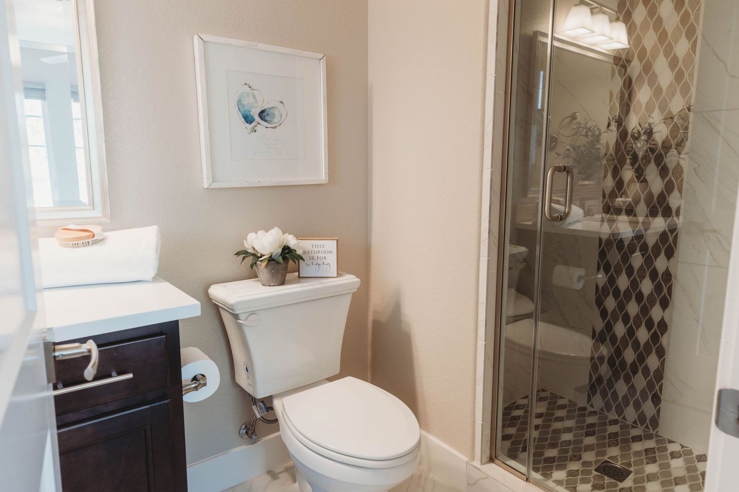 Contemporary bathroom with dark vanity, geometric shower door, and blue butterfly artwork.