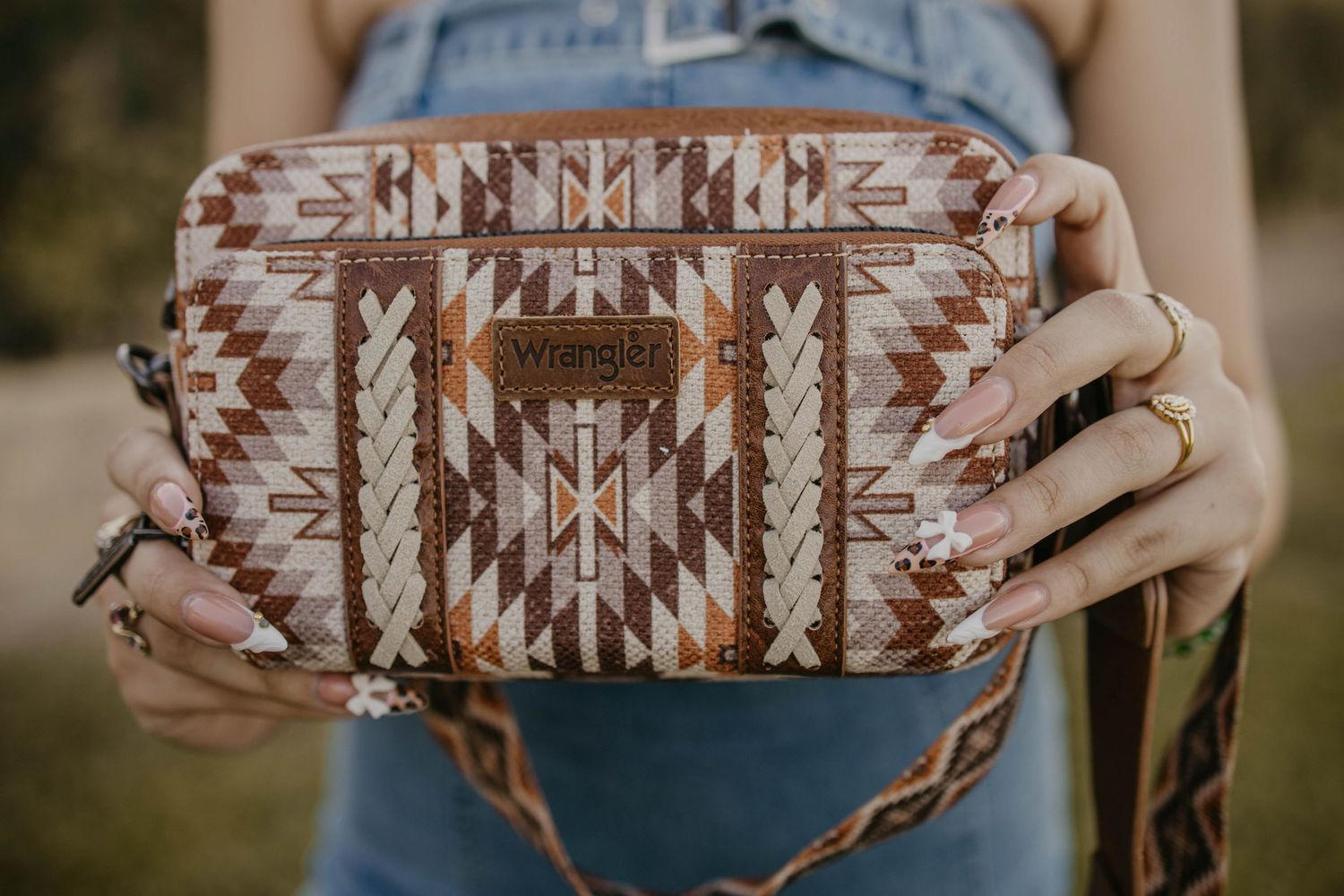 Hands holding brown and white southwestern pattern wallet with geometric designs.