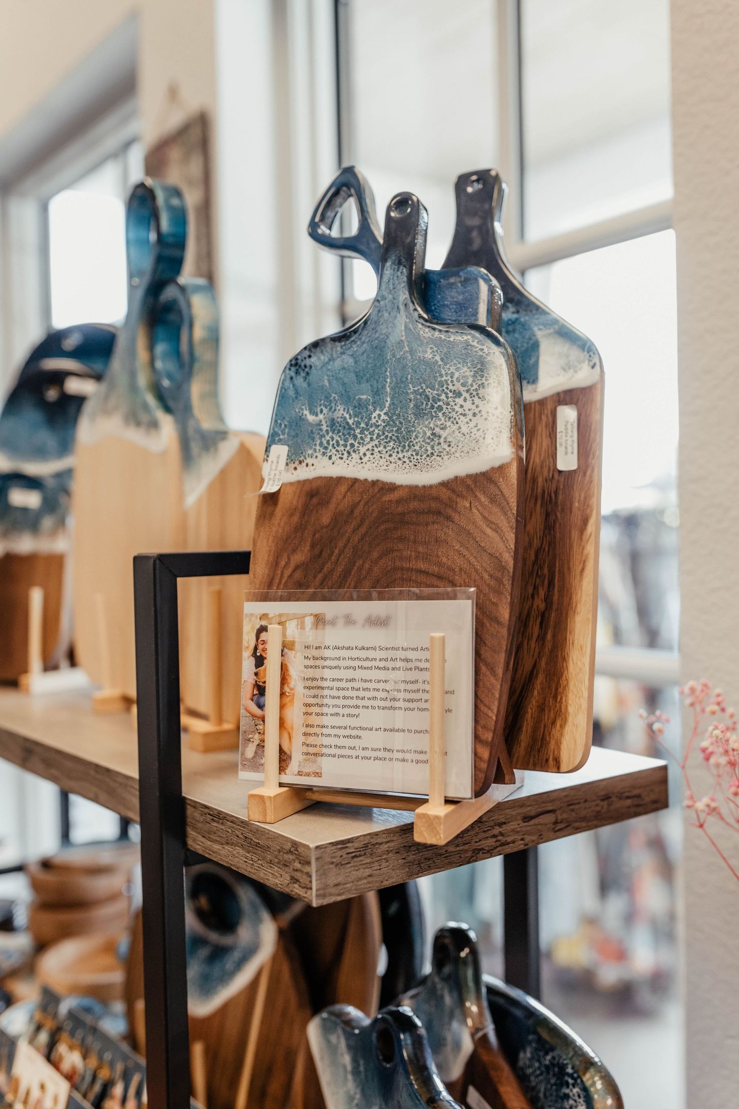 Wooden cutting boards with blue resin wave designs displayed on retail shelving.
