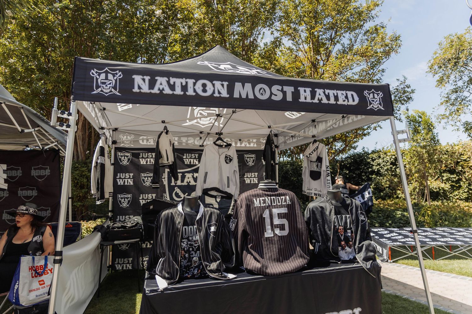 Nation Most Hated merchandise tent displaying Raiders jerseys and apparel at an outdoor fan event.