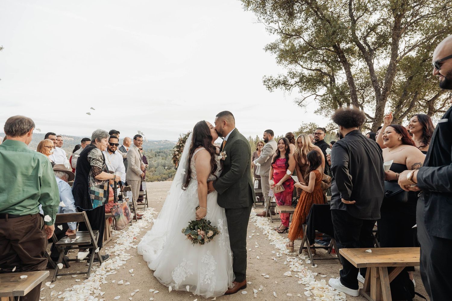 Guests throw confetti over the newlyweds at a scenic outdoor wedding celebration.