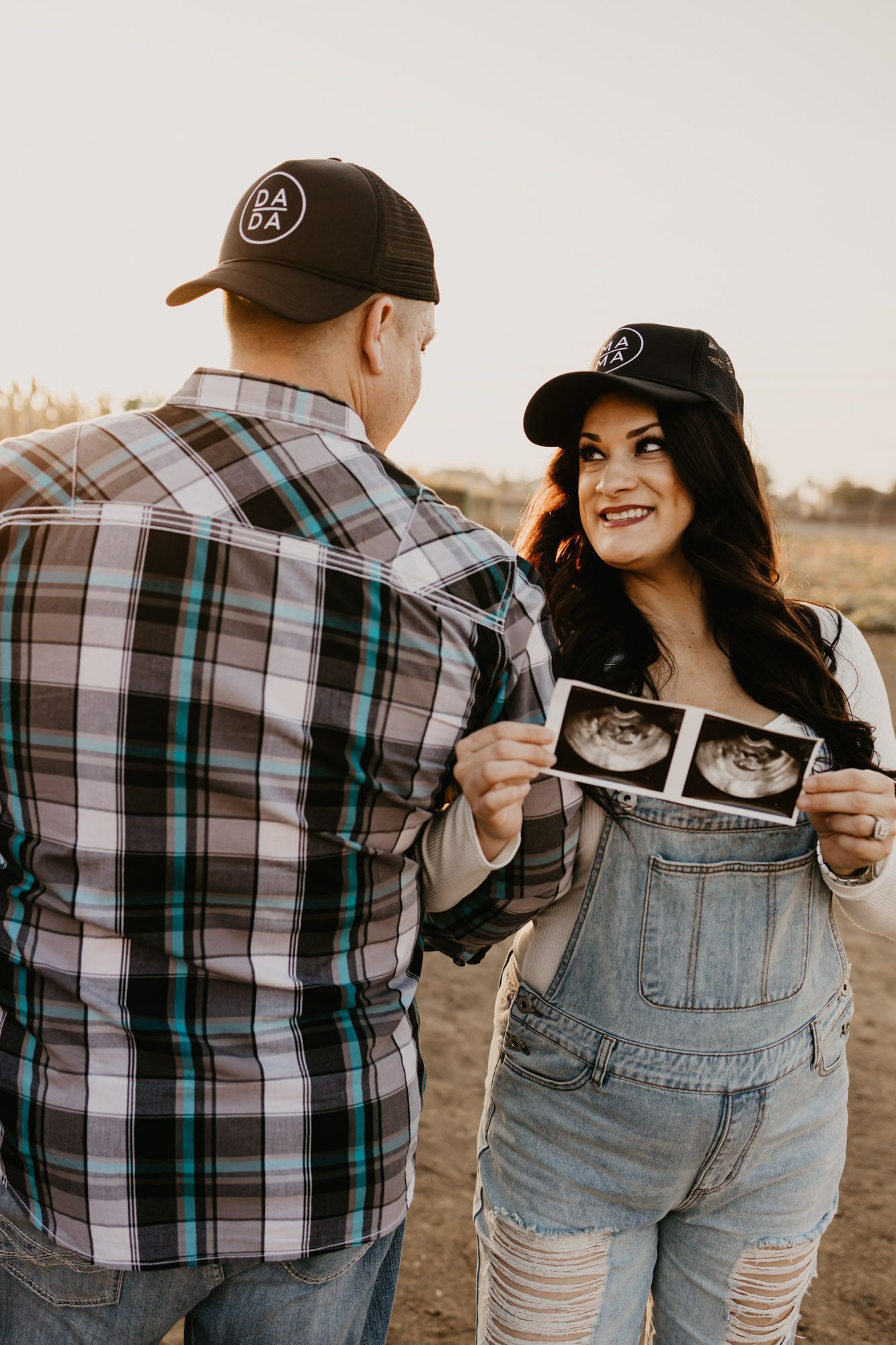 Expecting couple sharing ultrasound photos during outdoor photoshoot.