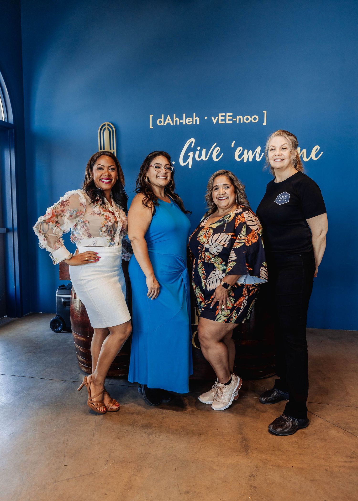 People posing casually against blue wall with text decoration in social setting.