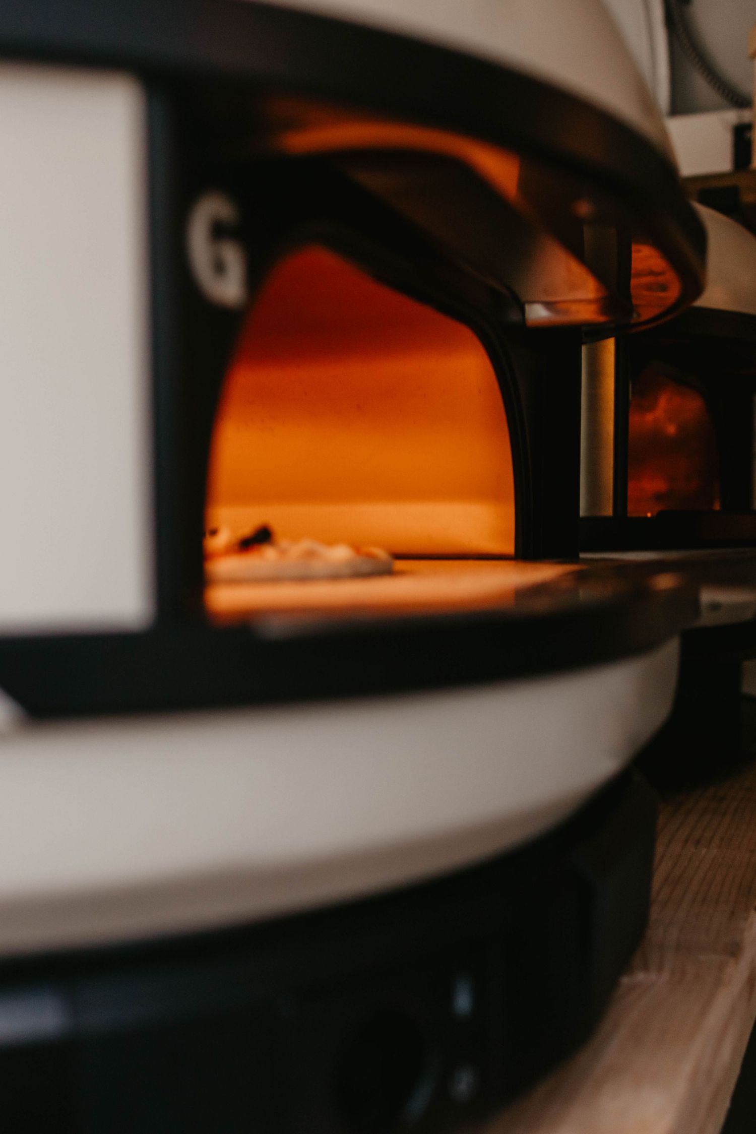 Close-up view of an illuminated pizza oven with an orange glow inside.