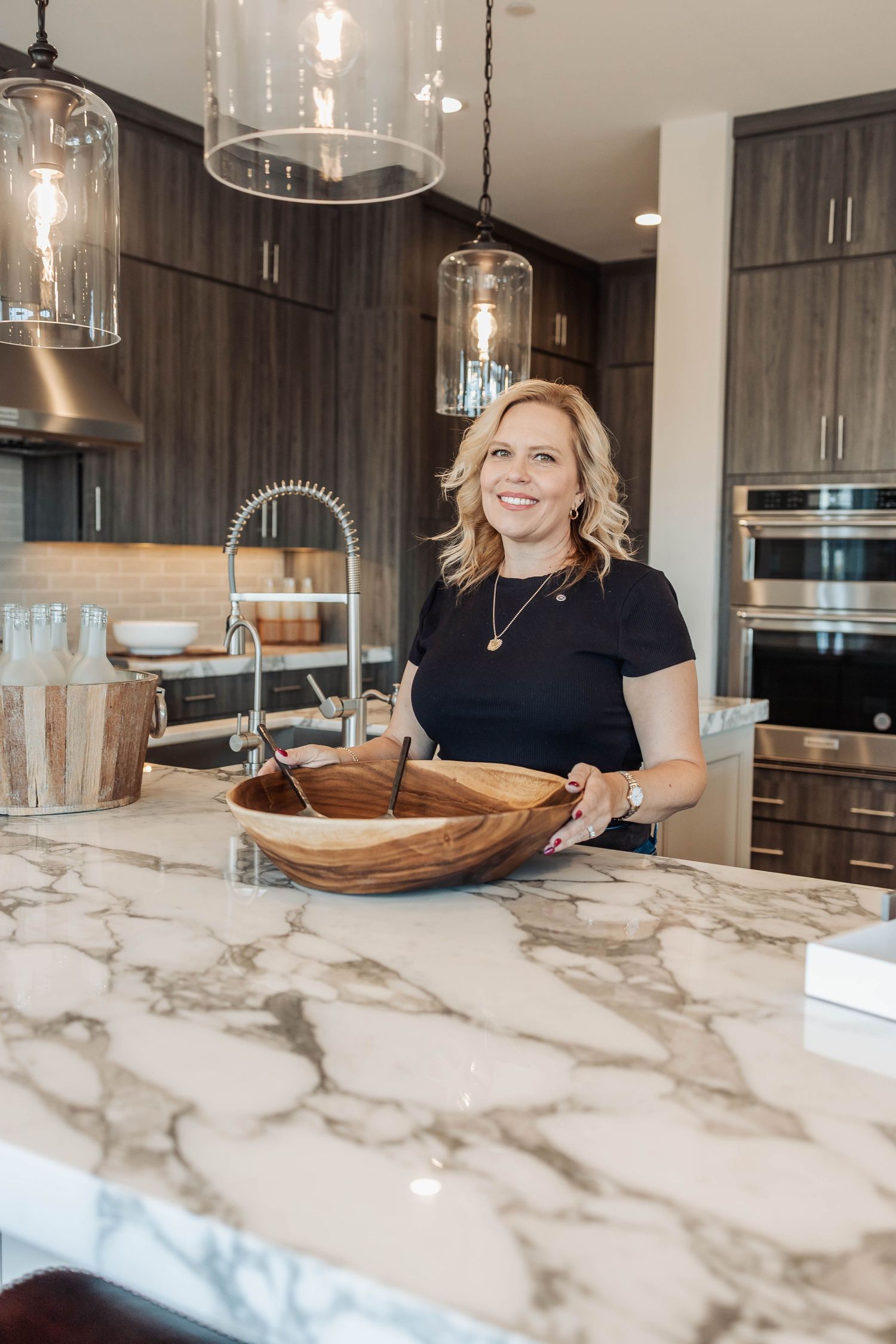 Modern kitchen with marble countertops, glass pendant lights, and dark wood cabinets.