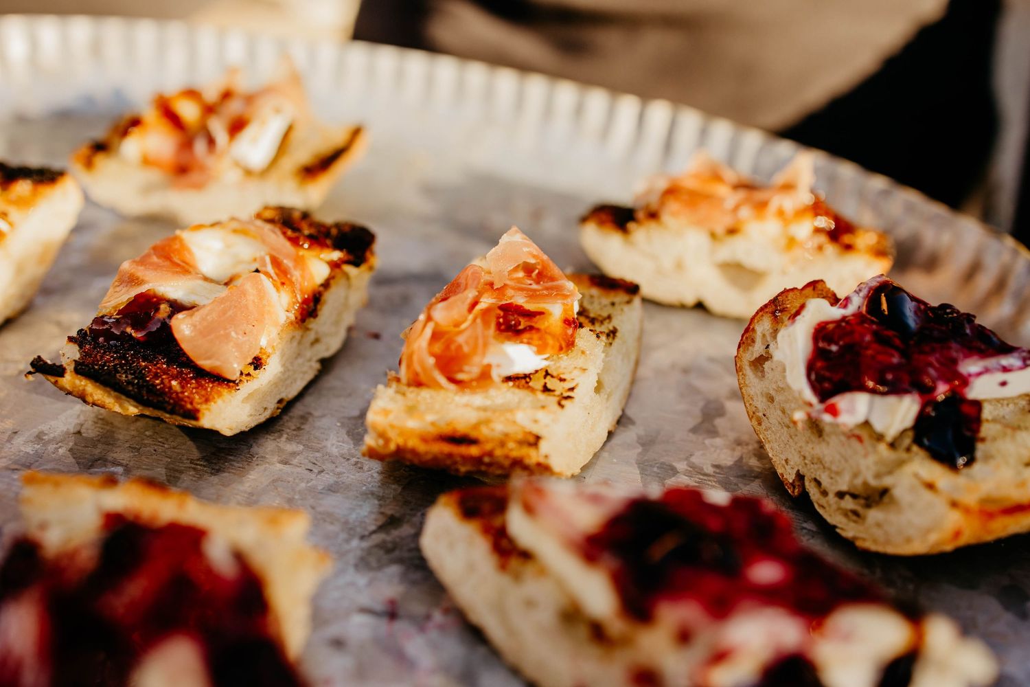 Grilled flatbreads topped with colorful ingredients arranged on a rustic cooking surface.