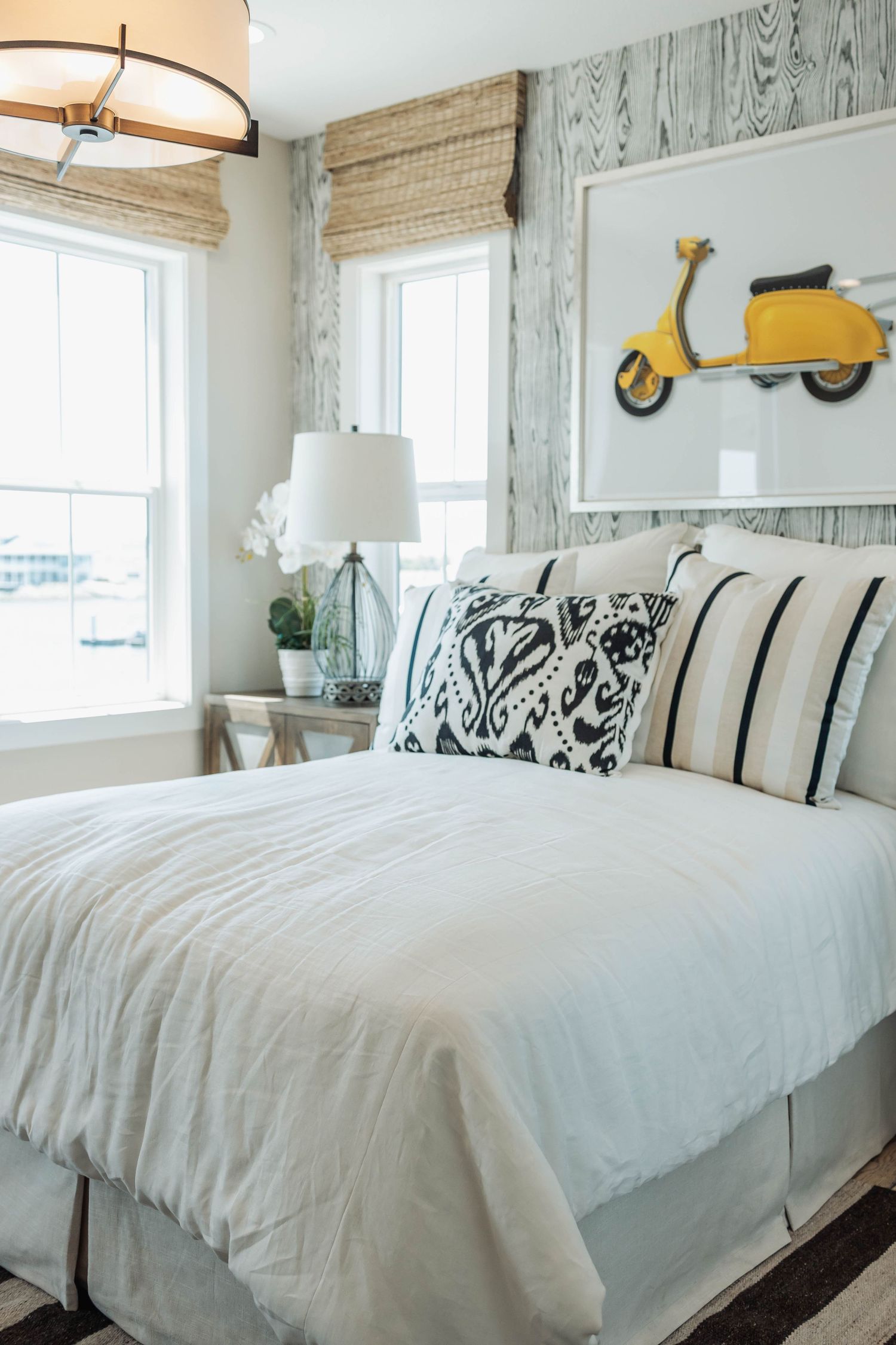 Coastal themed bedroom with whitewashed wood walls and crisp white bedding accented by striped pillows.