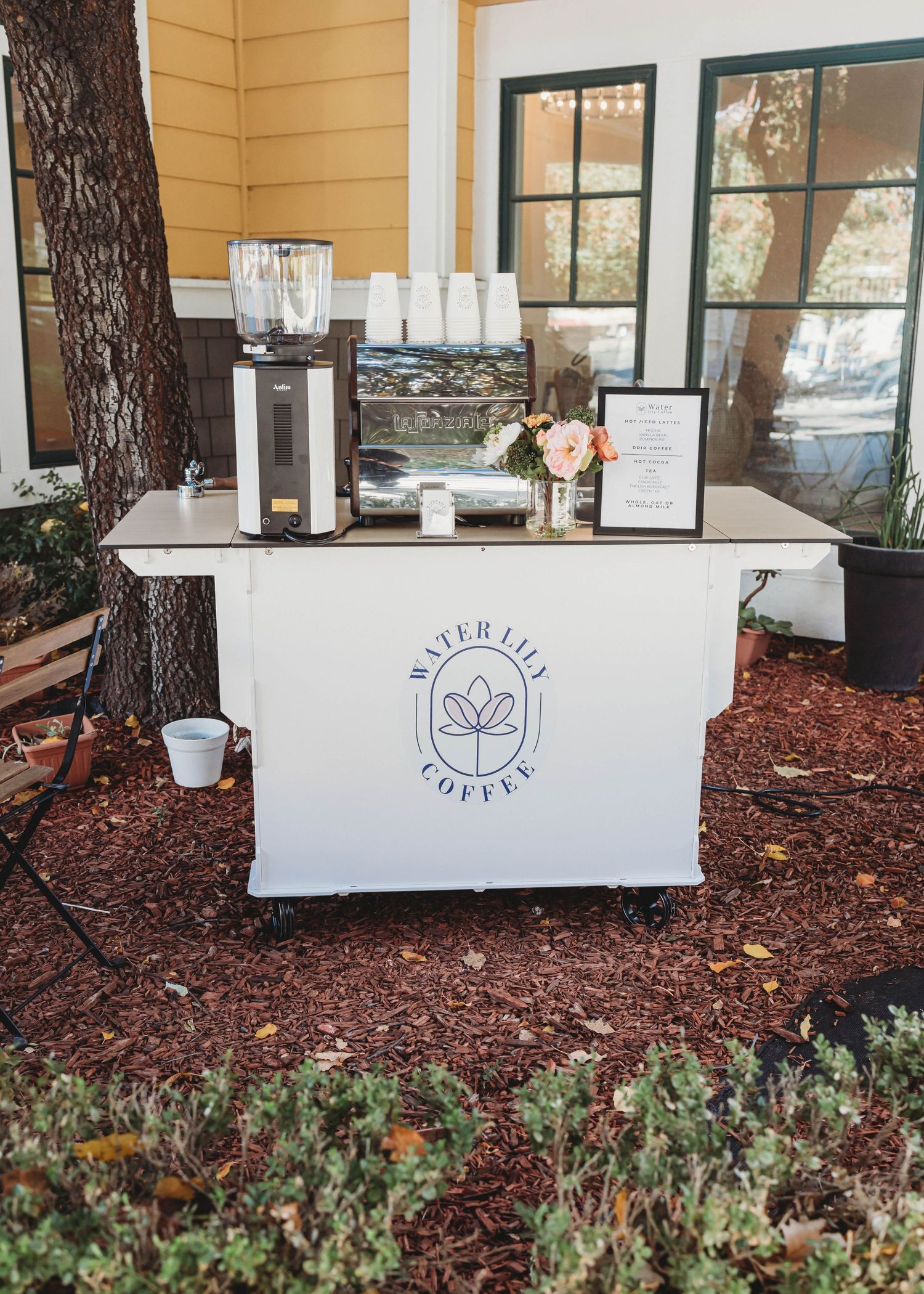 White exterior of a coffee shop with large windows and mulch landscaping.