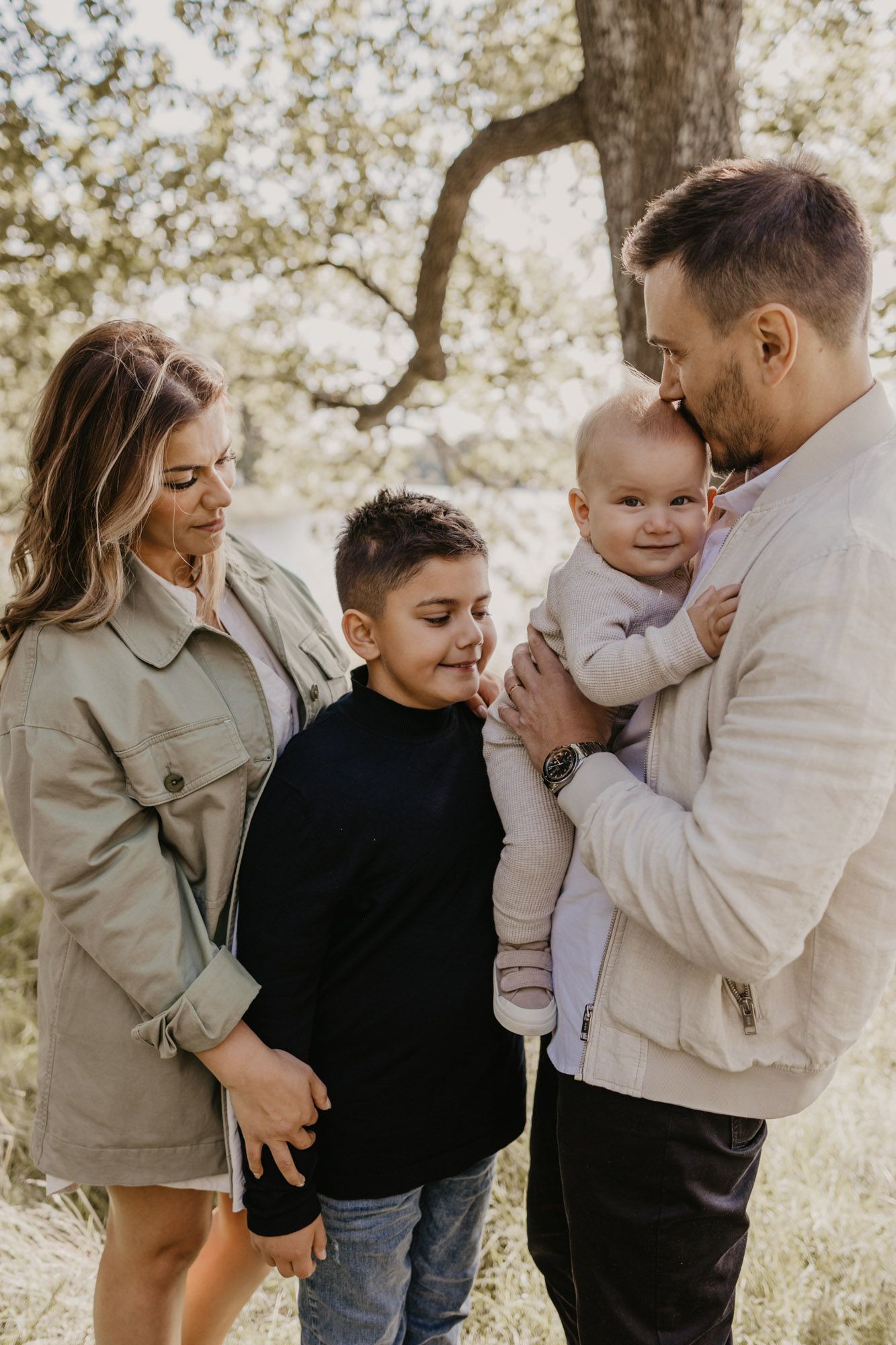 Heartwarming family moment captured in golden sunlight under trees.