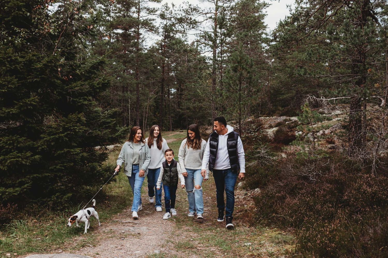 A casual group hike through a wooded area with a small dog leading the way.