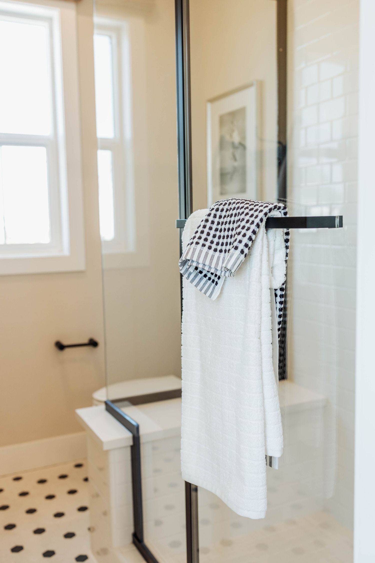 Modern bathroom featuring black hardware and white towels on minimalist towel bars.