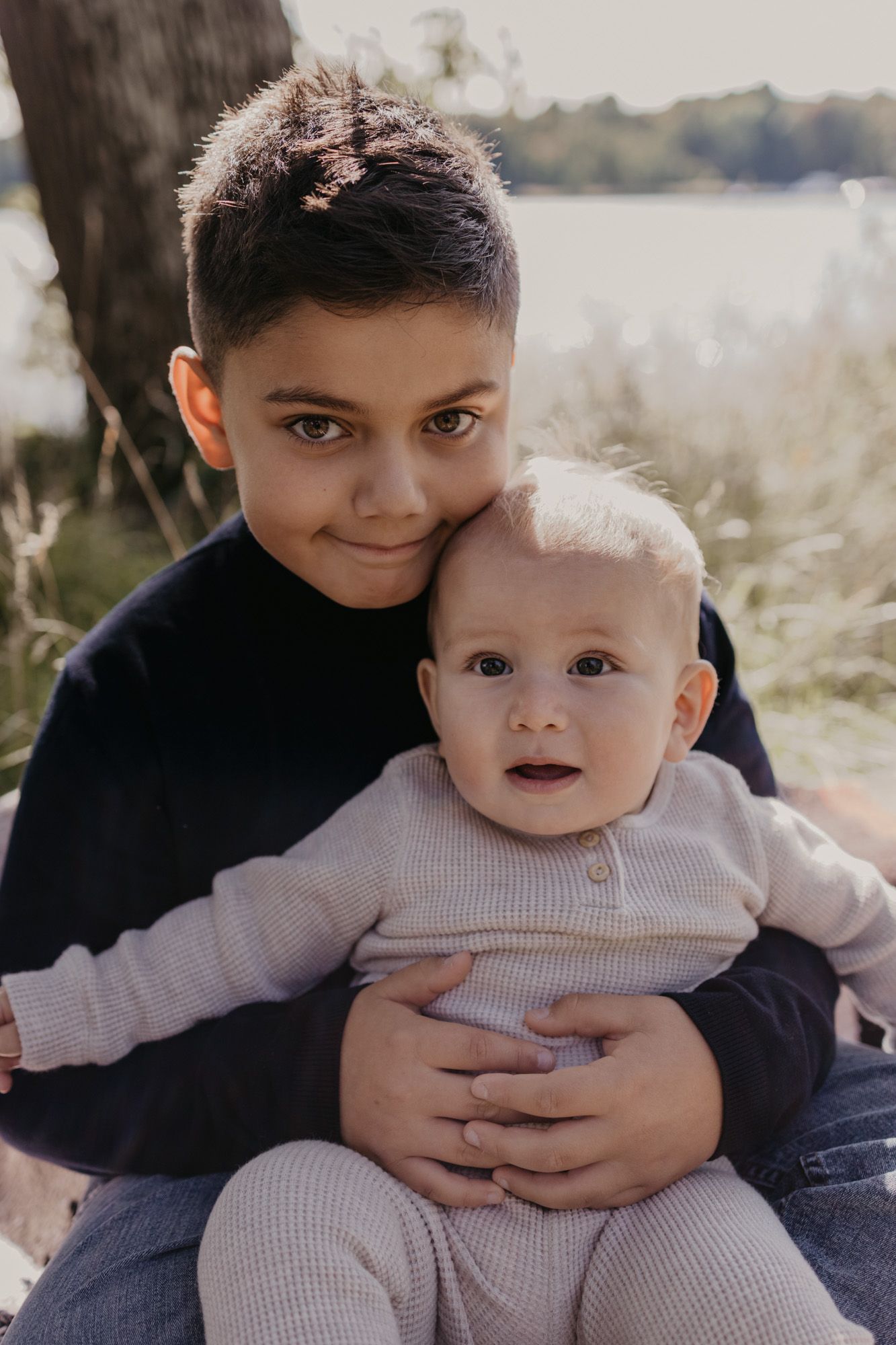 Two siblings sharing a tender moment together in natural outdoor lighting.