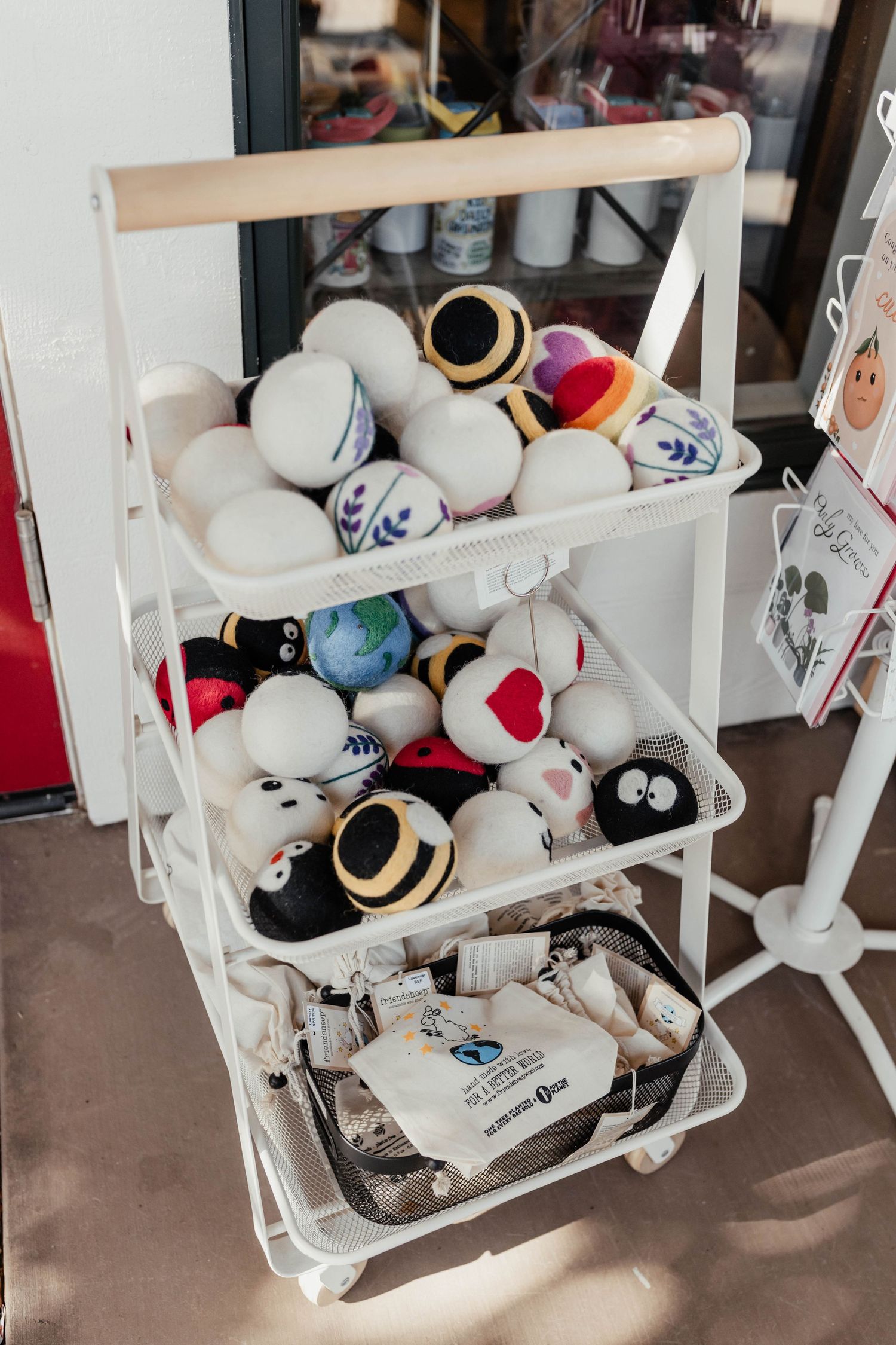White tiered shelf displaying plush toys and decorative balls in retail setting.